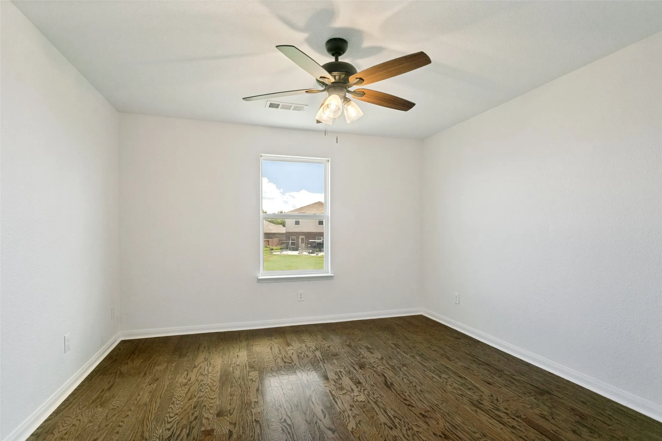 Room featuring dark wood-finish flooring, white walls, and a ceiling fan with integrated lighting