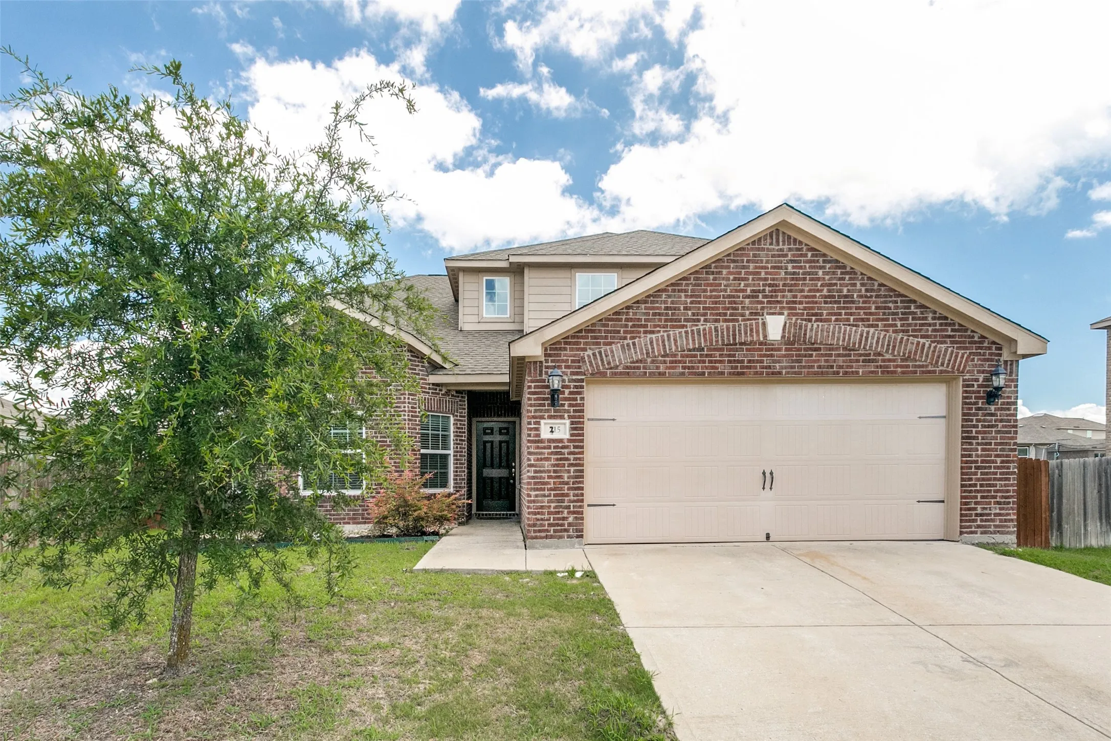 Brick and siding exterior featuring a two-car garage with an arched brick detail