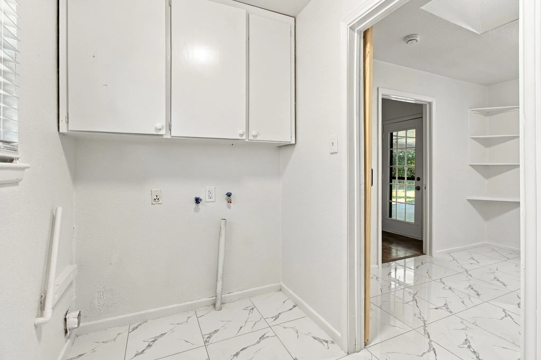 White cabinetry, window with blinds, white wall finishes, tile flooring, built-in shelving
