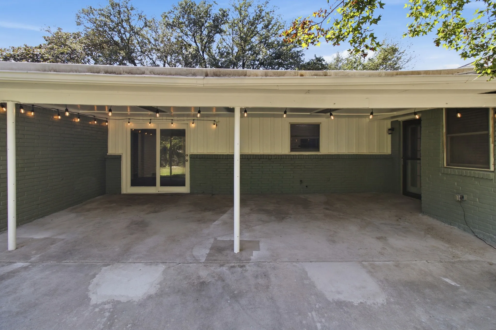 Covered patio with concrete flooring, supported by white posts
