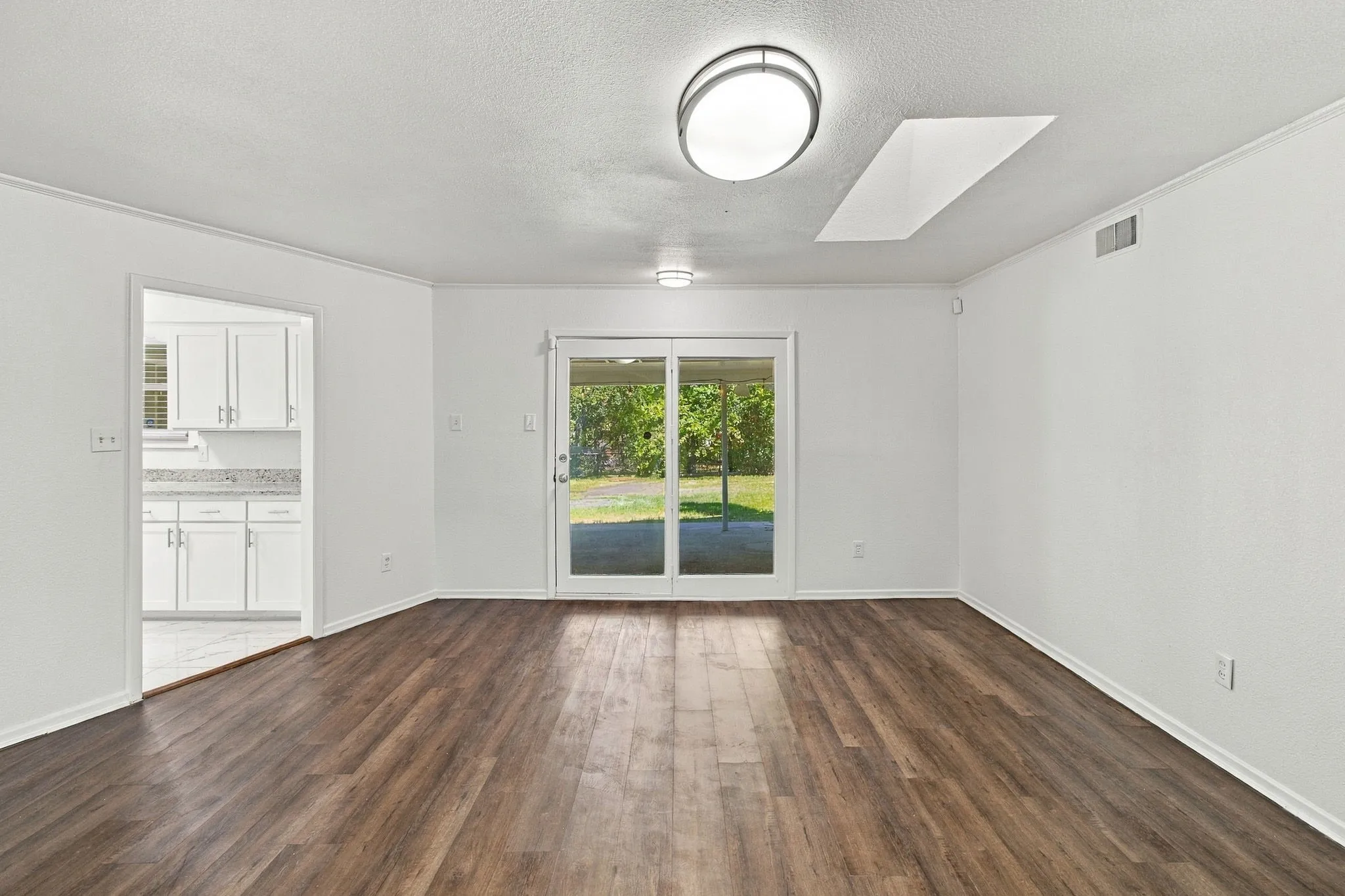 Wood-finish flooring throughout, white painted walls, and a ceiling-mounted light fixture