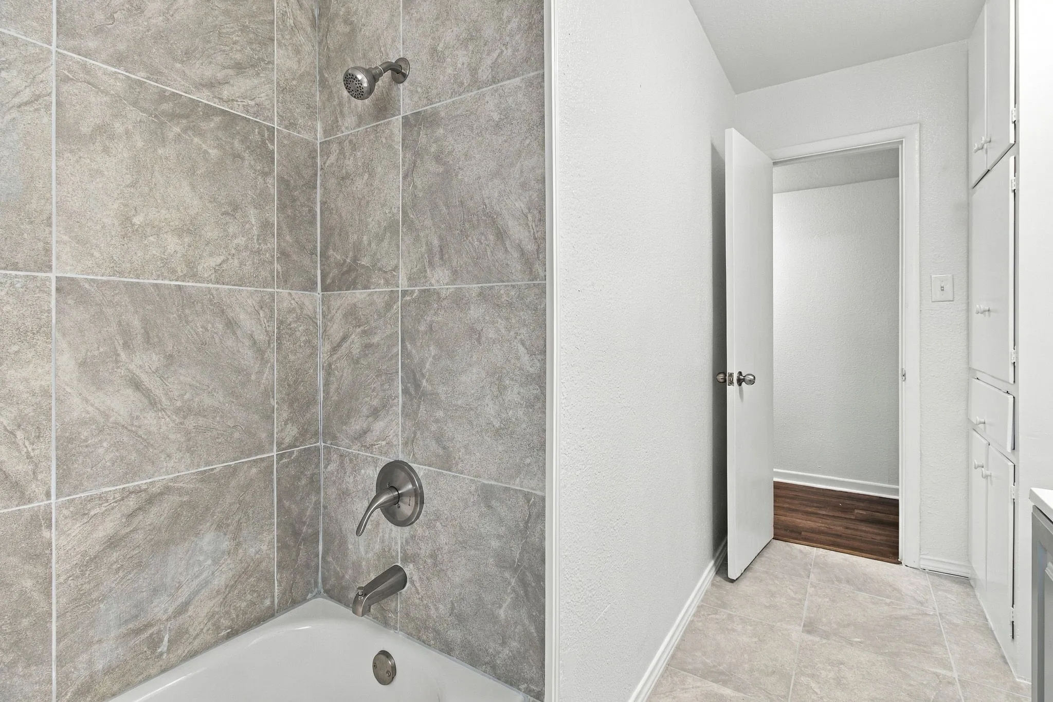 Bathtub with brushed nickel fixtures and gray tile surround