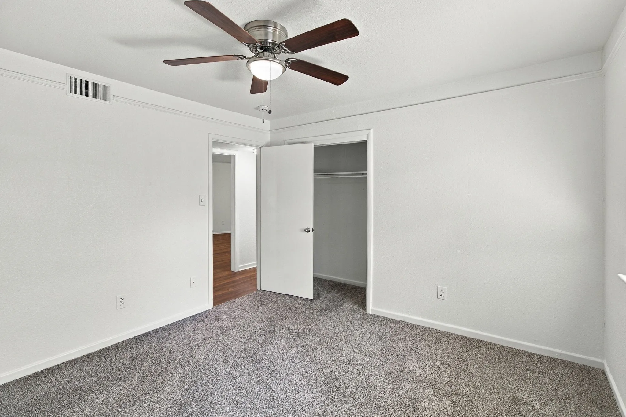 Ceiling fan with integrated lighting, plush grey carpeting, white interior doors, and crown molding
