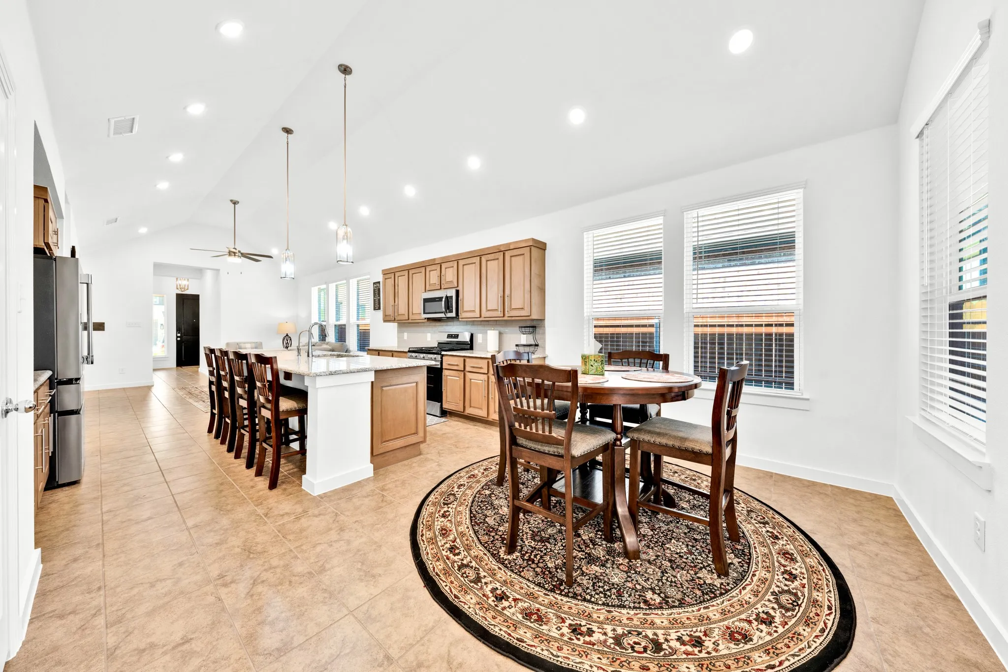 Vaulted ceiling kitchen featuring recessed lighting, a center island with bar seating, wood cabinetry, and tile flooring