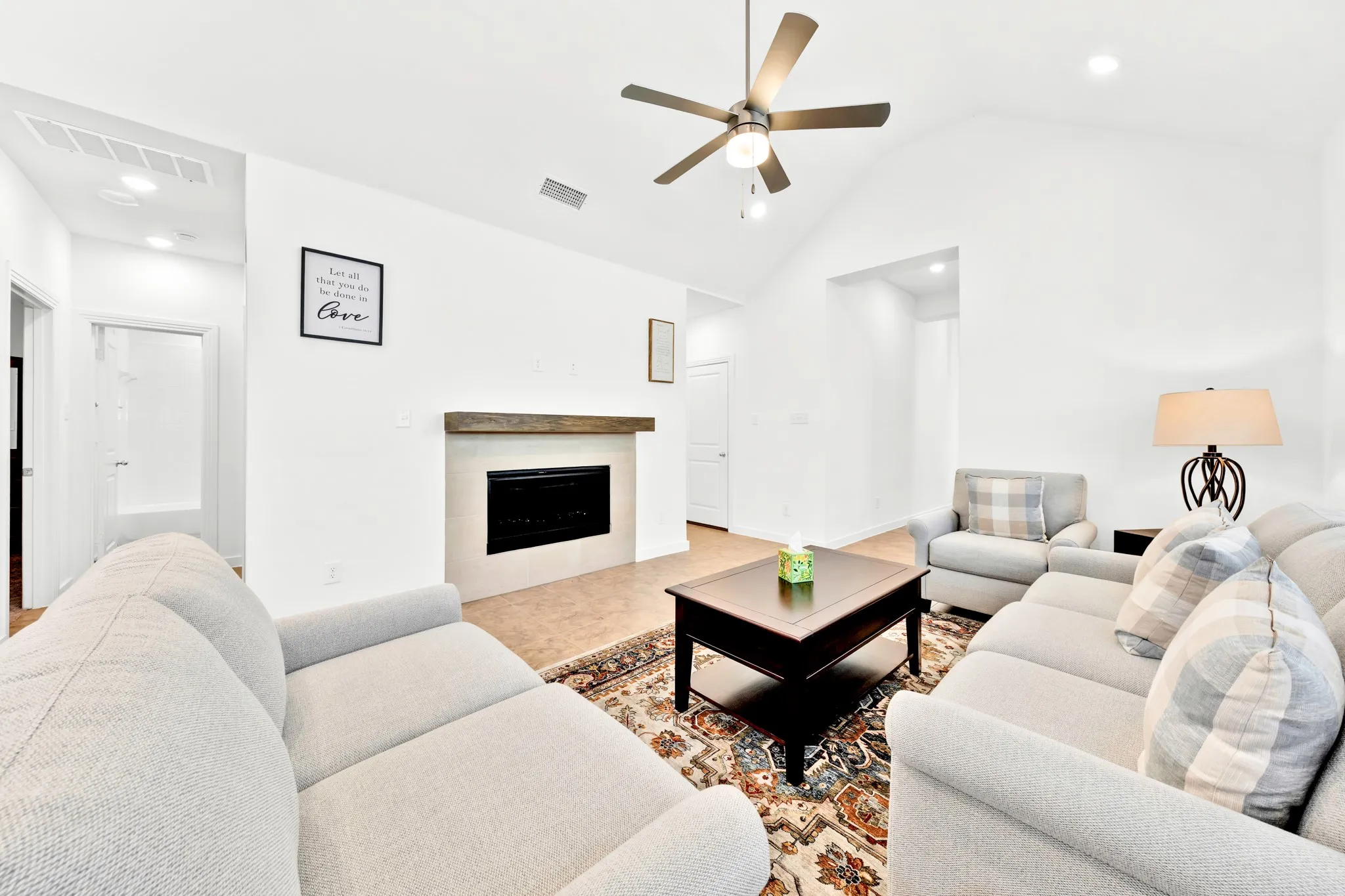 Vaulted ceiling with an integrated ceiling fan, fireplace with a wood mantel, tile flooring, recessed lighting, and a white interior