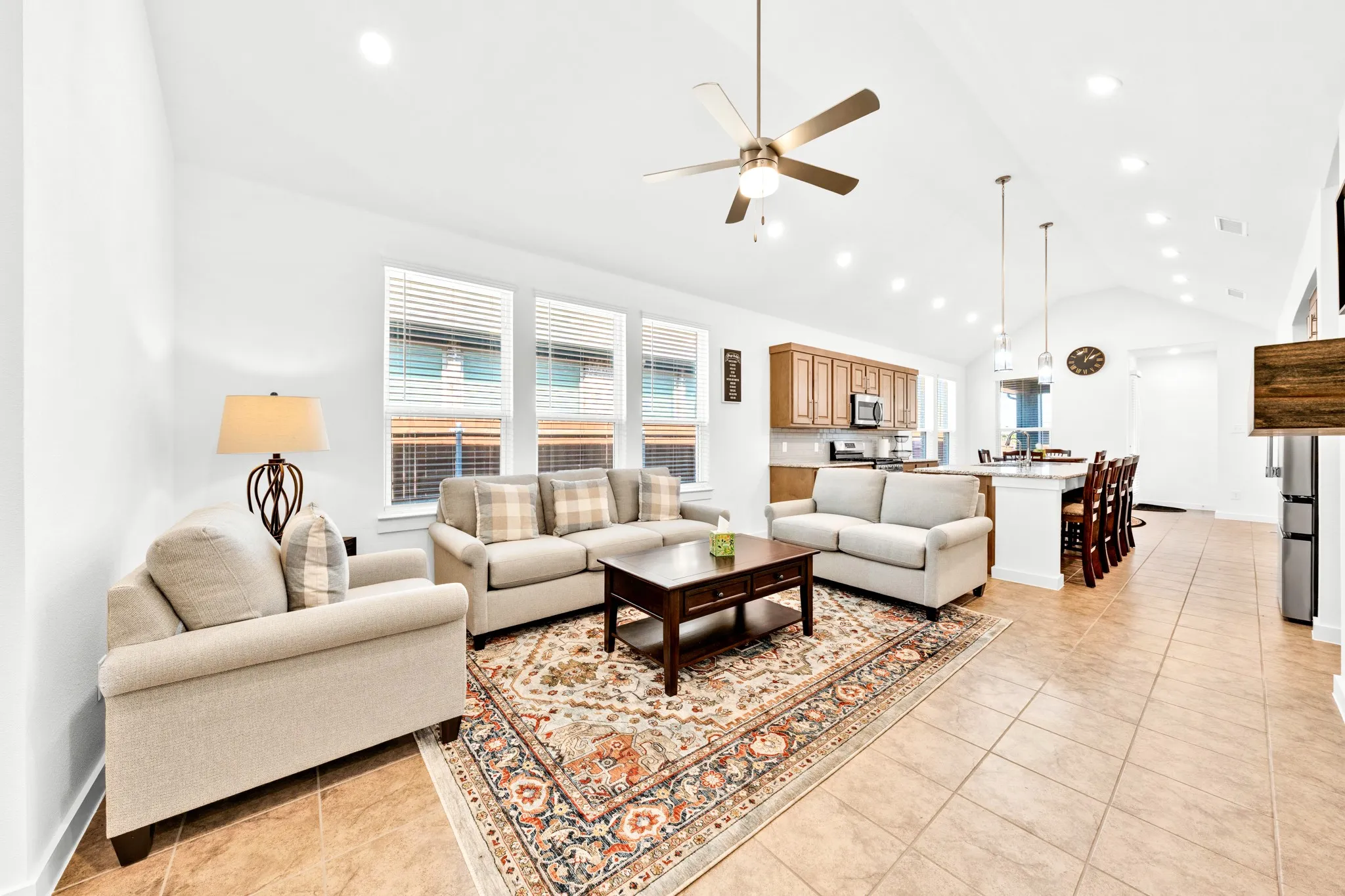 Vaulted ceilings with recessed lighting, ceiling fan, tile flooring, and a kitchen island with pendant lighting