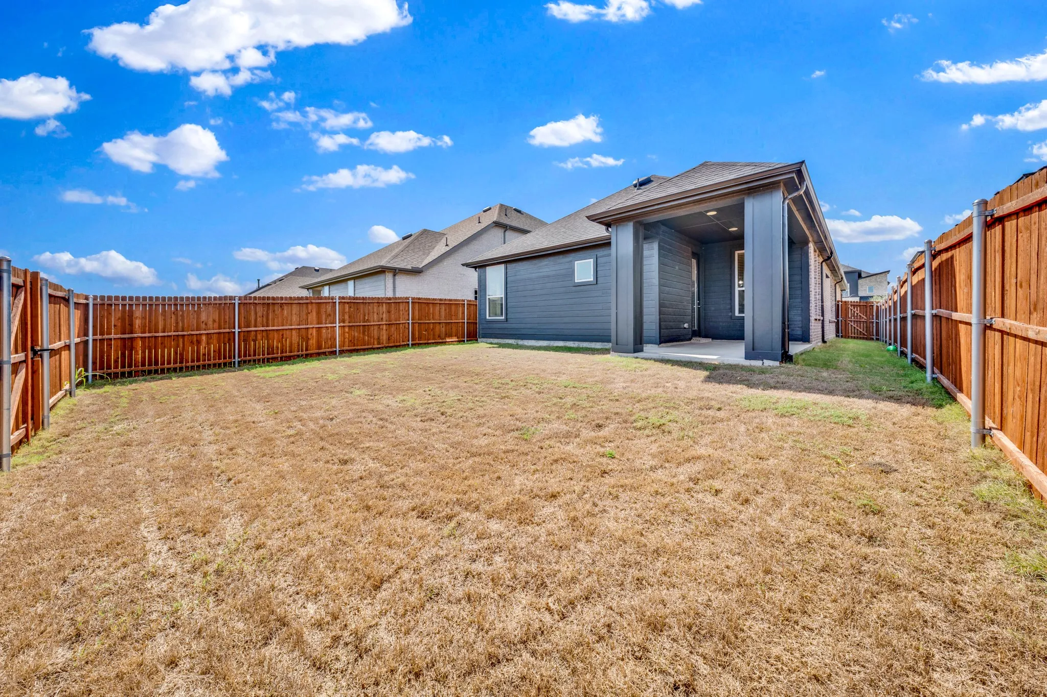 Expansive backyard with wood fencing and a covered patio