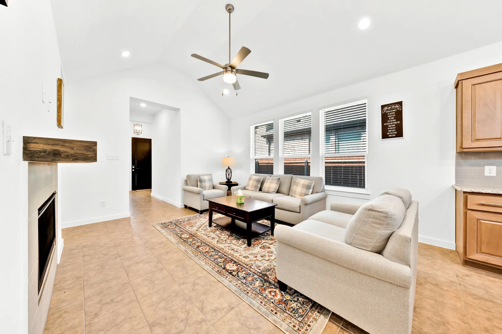 Vaulted ceiling with a ceiling fan, recessed lighting, tile flooring, built-in fireplace, and kitchen cabinetry with a countertop