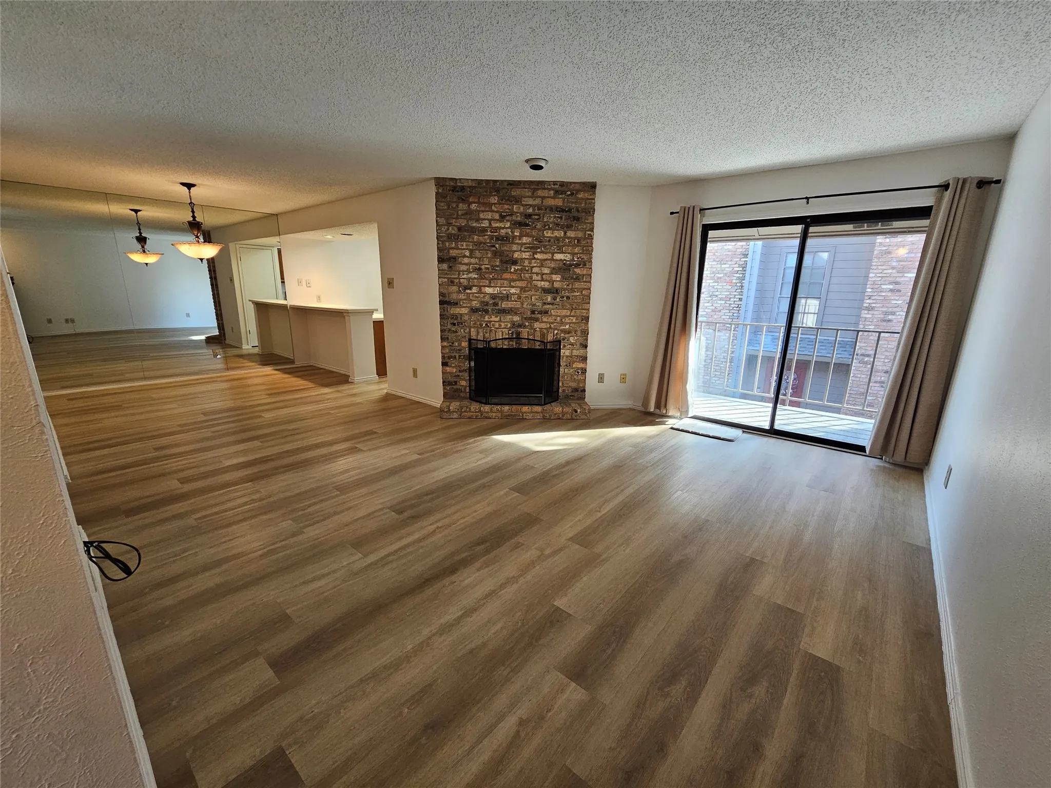 Living room featuring a brick fireplace, and balcony
