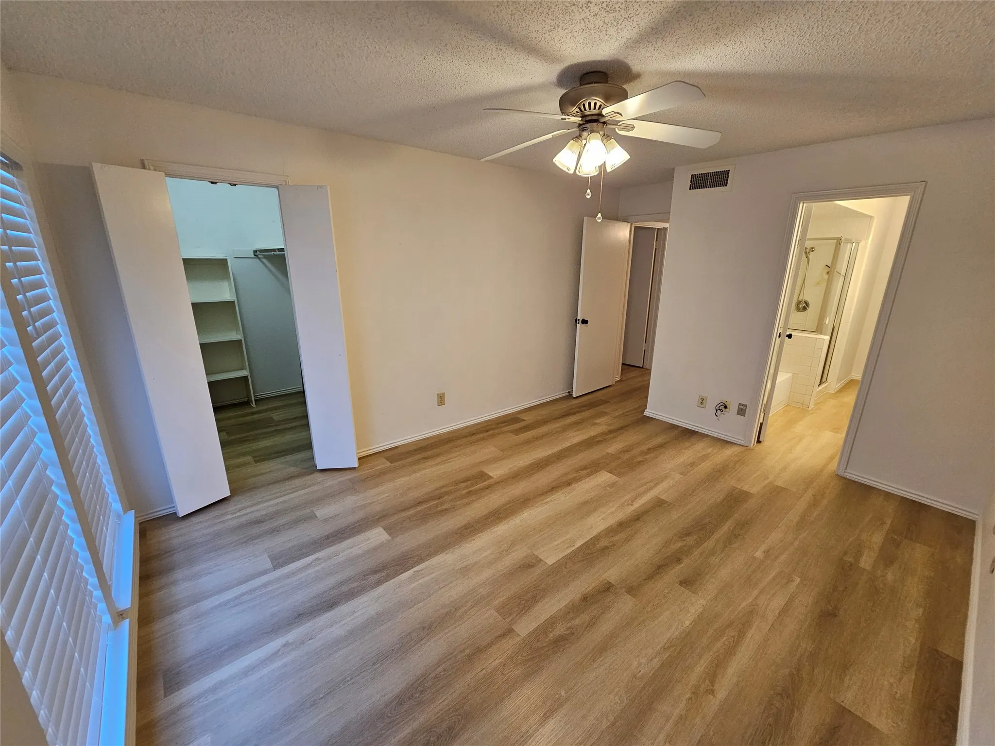 Primary bedroom featuring ensuite bathroom, spacious closet & ceiling fan