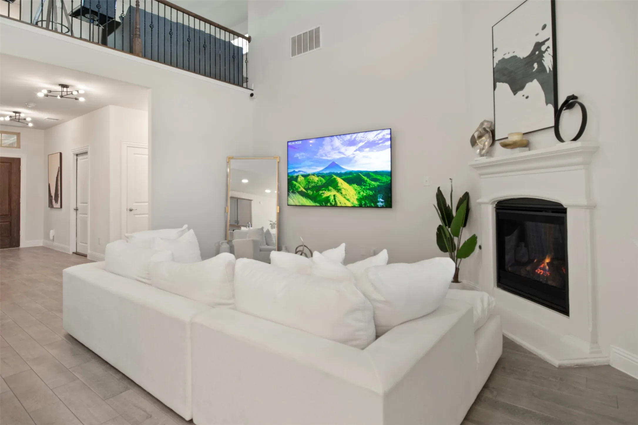Living area featuring a floor-to-ceiling fireplace with mantel and a second-story interior balcony with metal railing