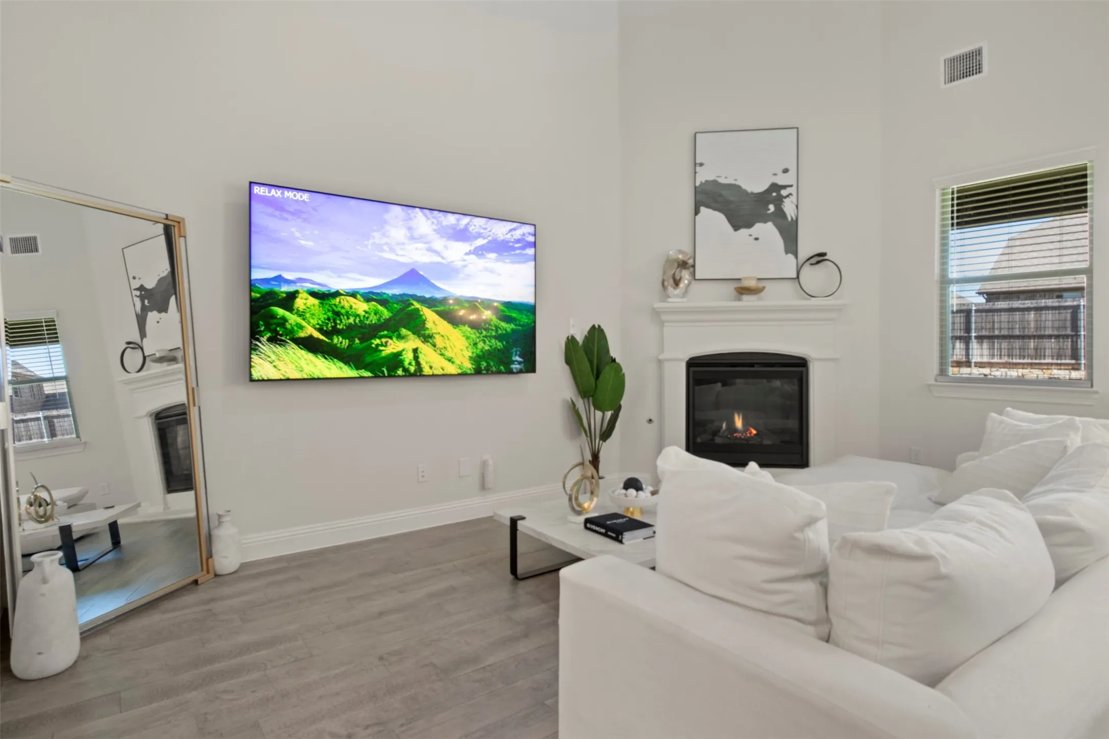 White walls with a corner fireplace, wood-finish flooring, and window with horizontal blinds