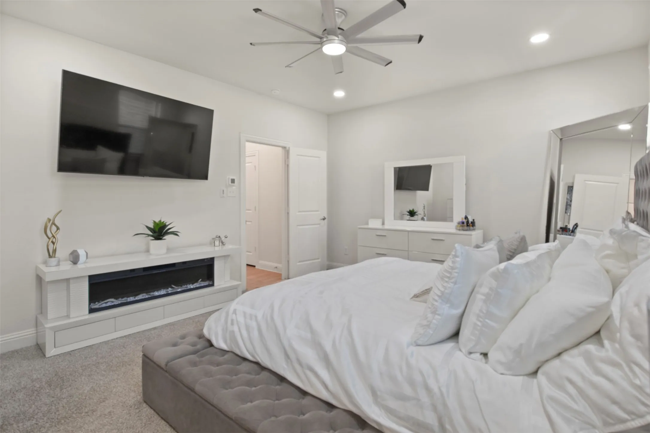 Recessed lighting, ceiling fan, white walls, and built-in electric fireplace
