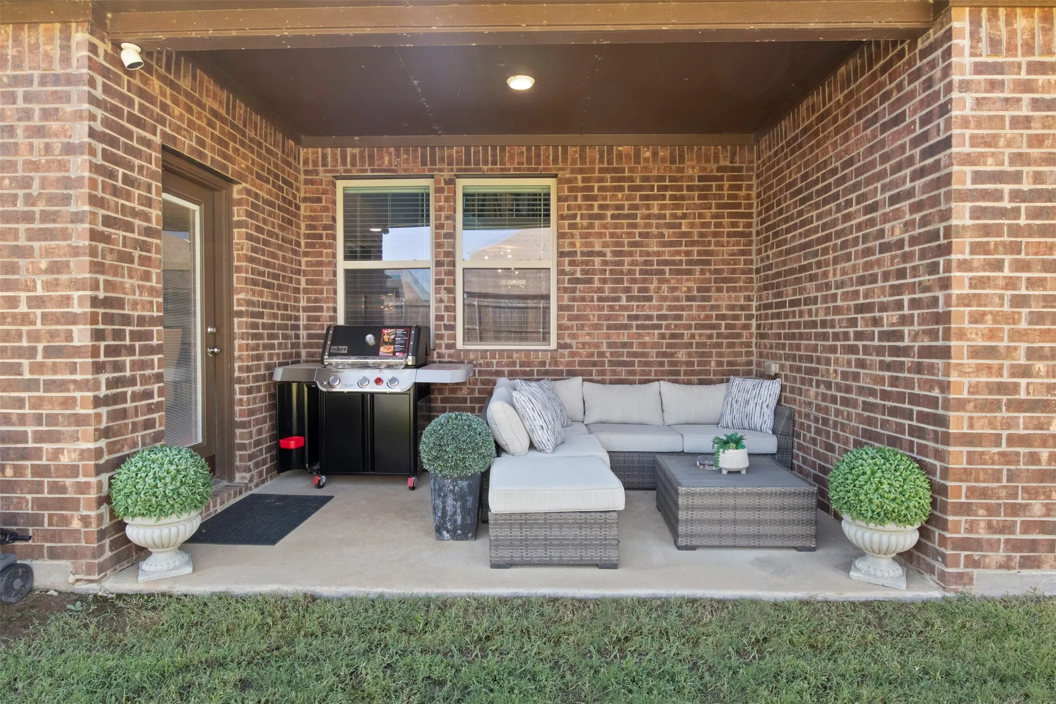Covered patio featuring brick construction, concrete flooring, and recessed lighting