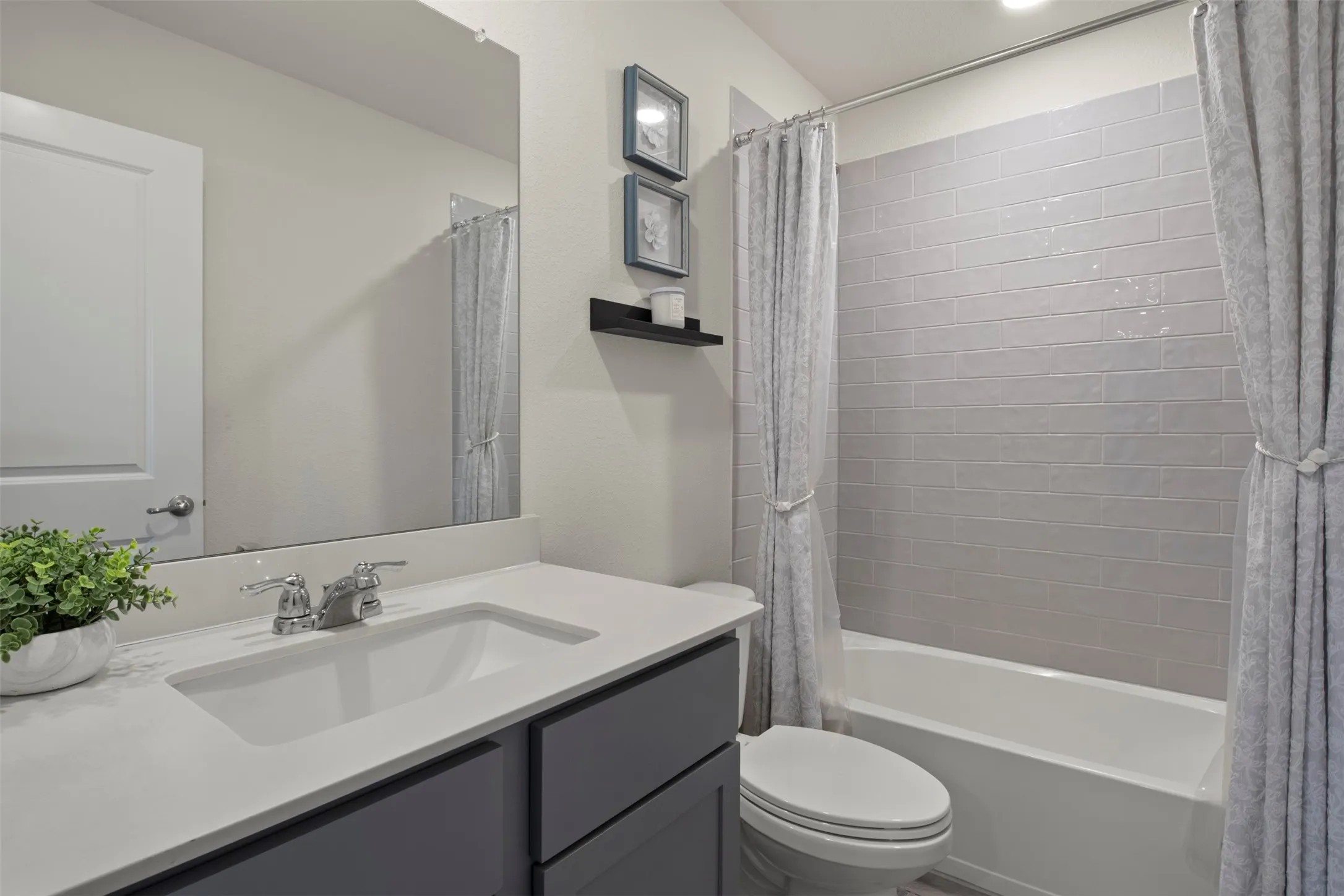 Bathroom featuring a built-in vanity with an integrated sink, polished chrome faucet, a white bathtub, and subway tile shower surround