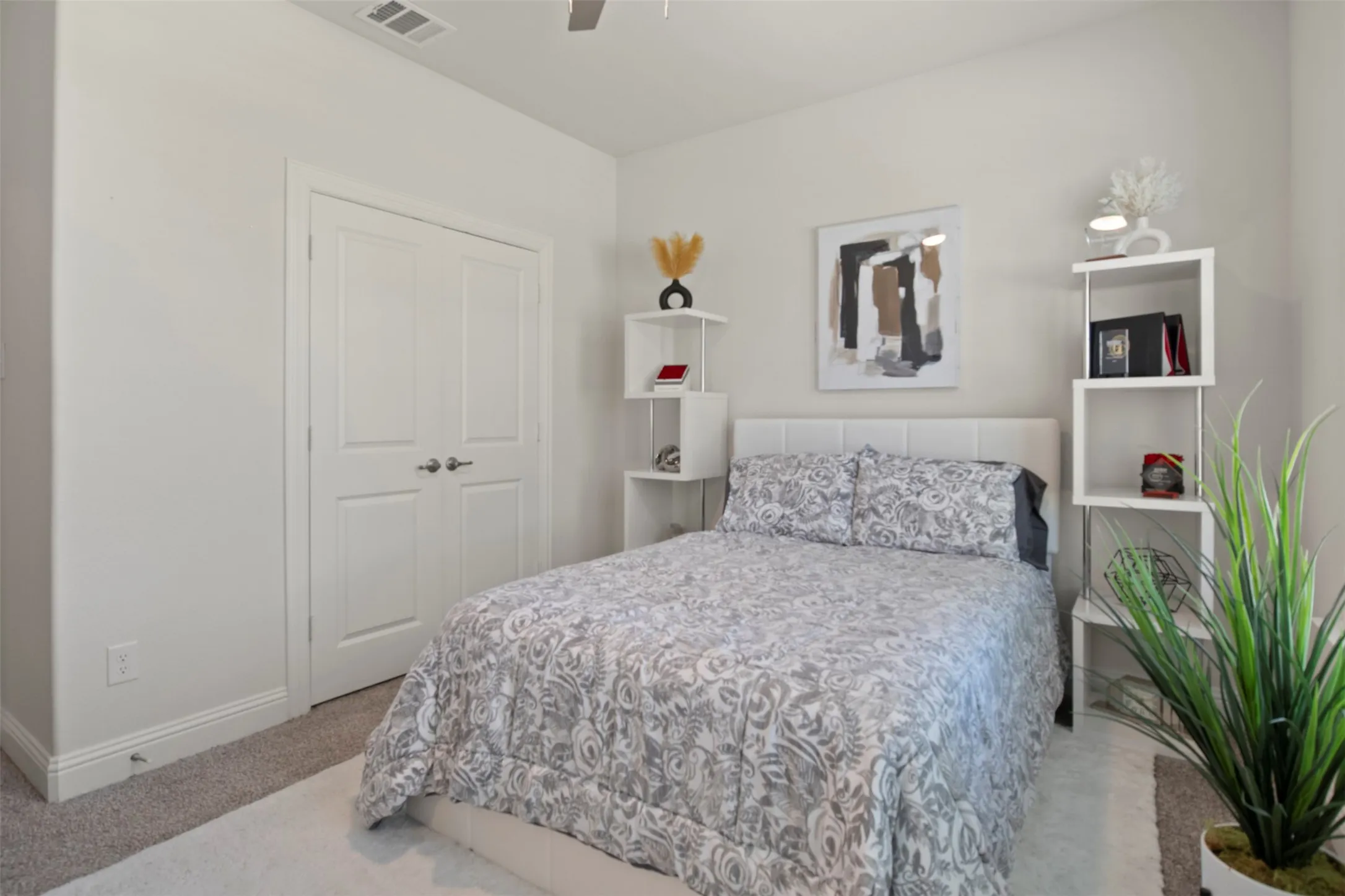 White interior walls, carpet flooring, a built-in closet with double doors, and a padded headboard