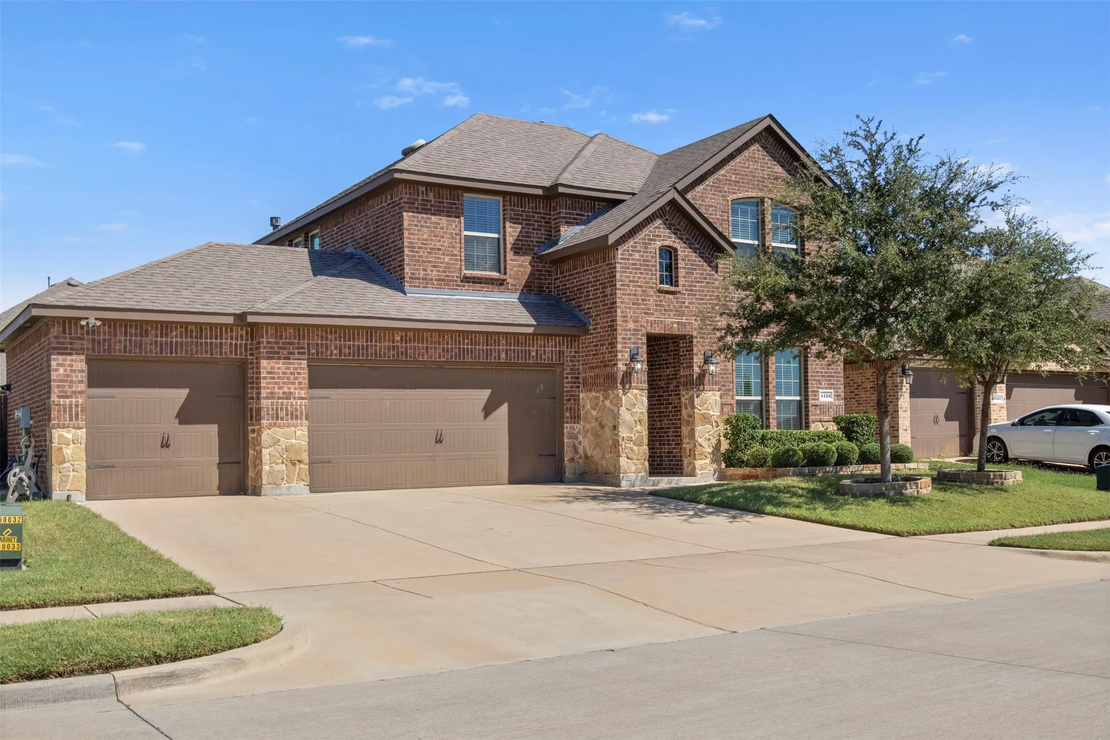 Brick exterior with stone accents, a multi-car garage, and established landscaping