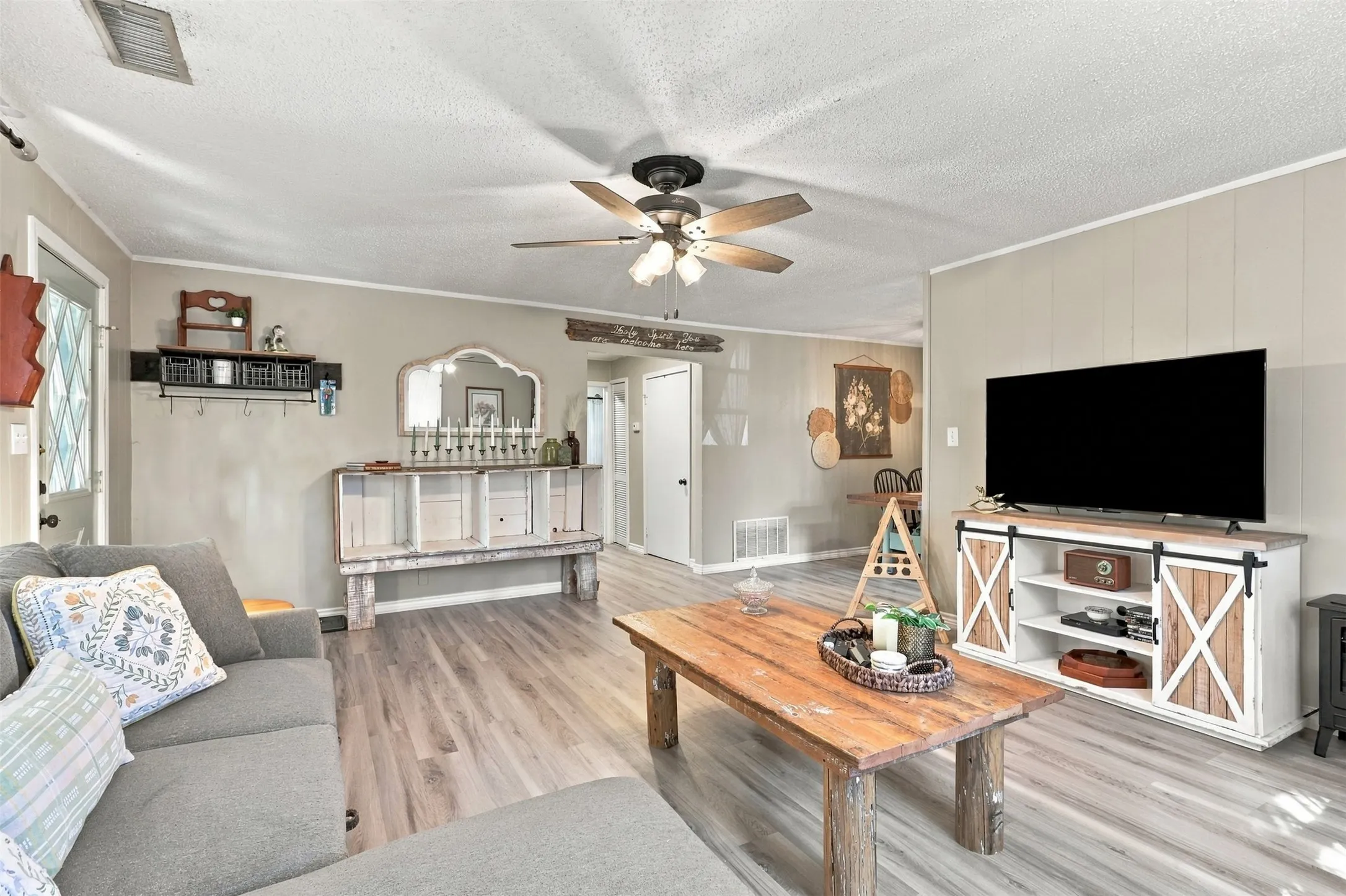 Wood-finish flooring, ceiling fan, board and batten wall paneling, and an entry door with a decorative glass insert