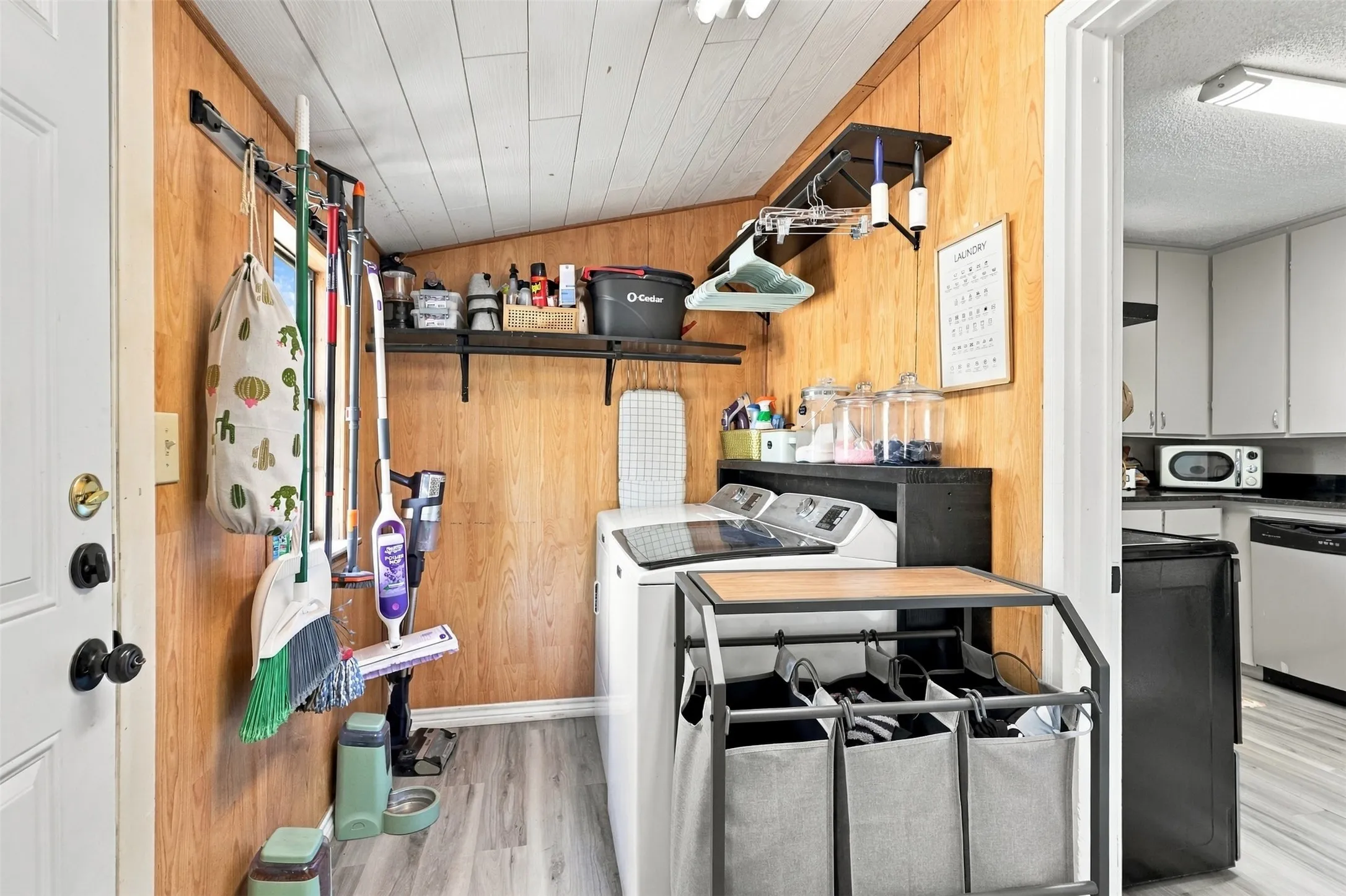 Laundry area featuring wood-finish wall paneling, slatted ceiling, and wood-finish flooring