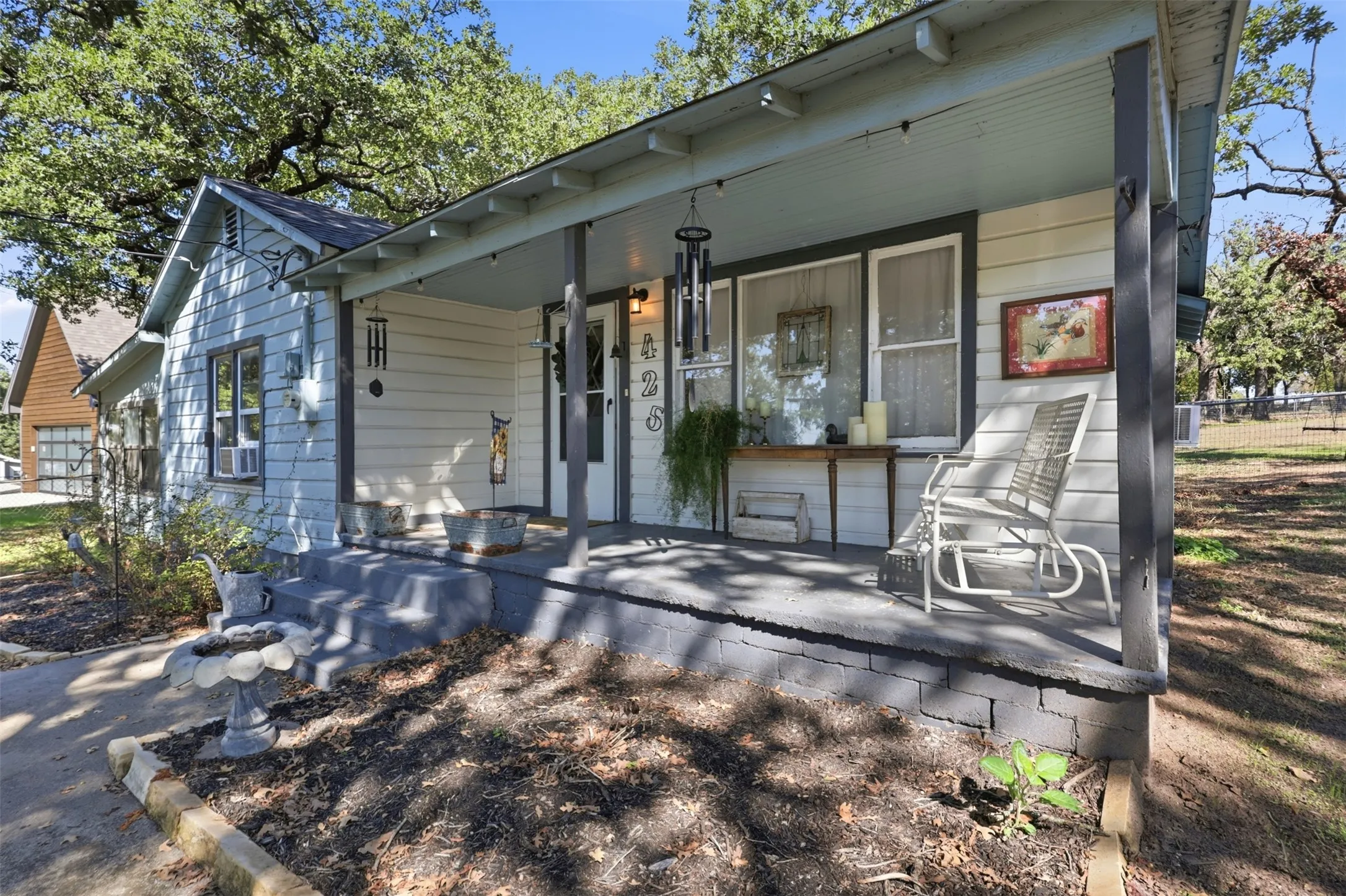 Front porch with a painted concrete surface, wood-paneled siding, and a covered entry