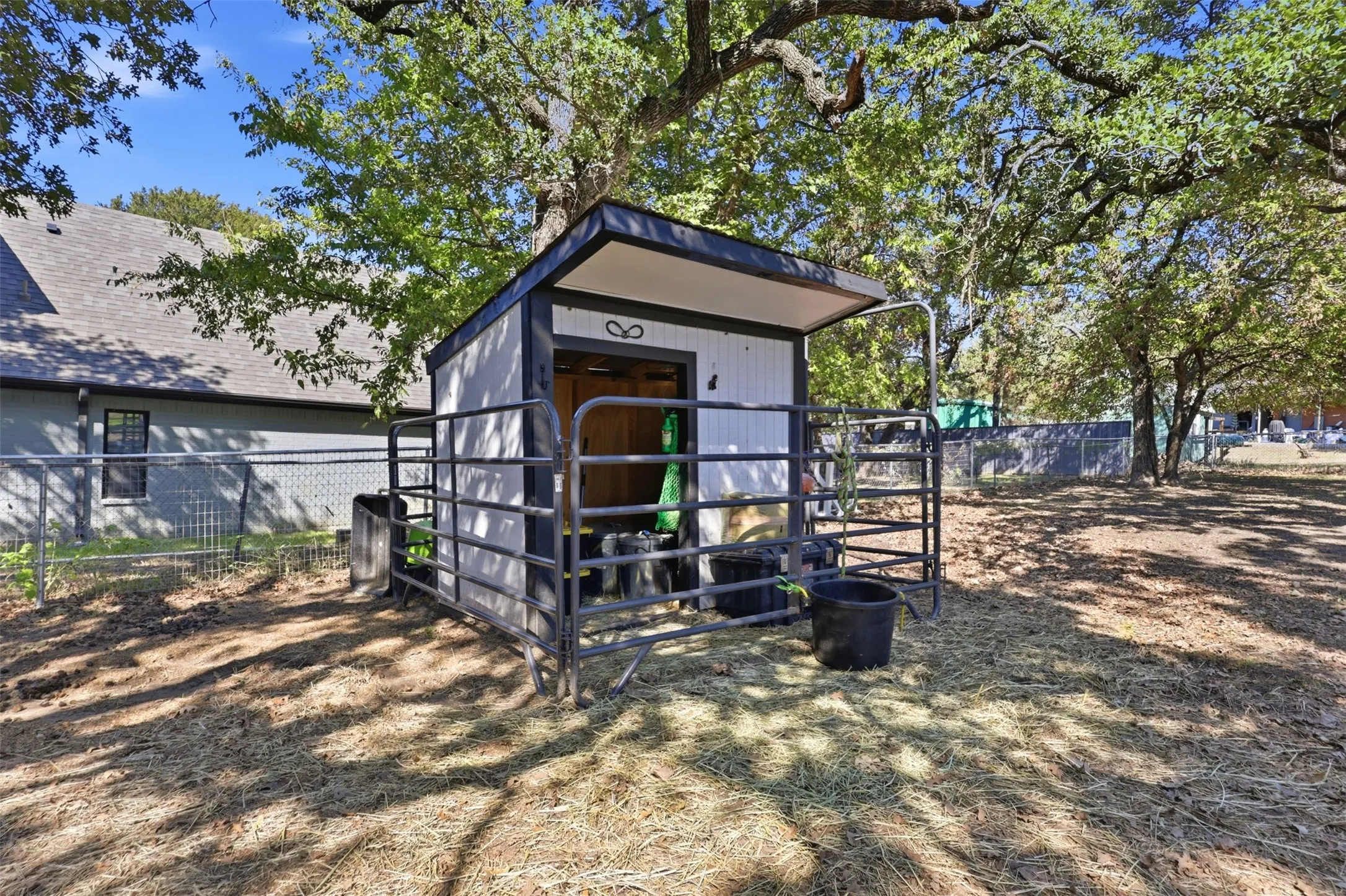 Fenced outdoor structure with an overhang, metal-paneled fencing, and a gravel base