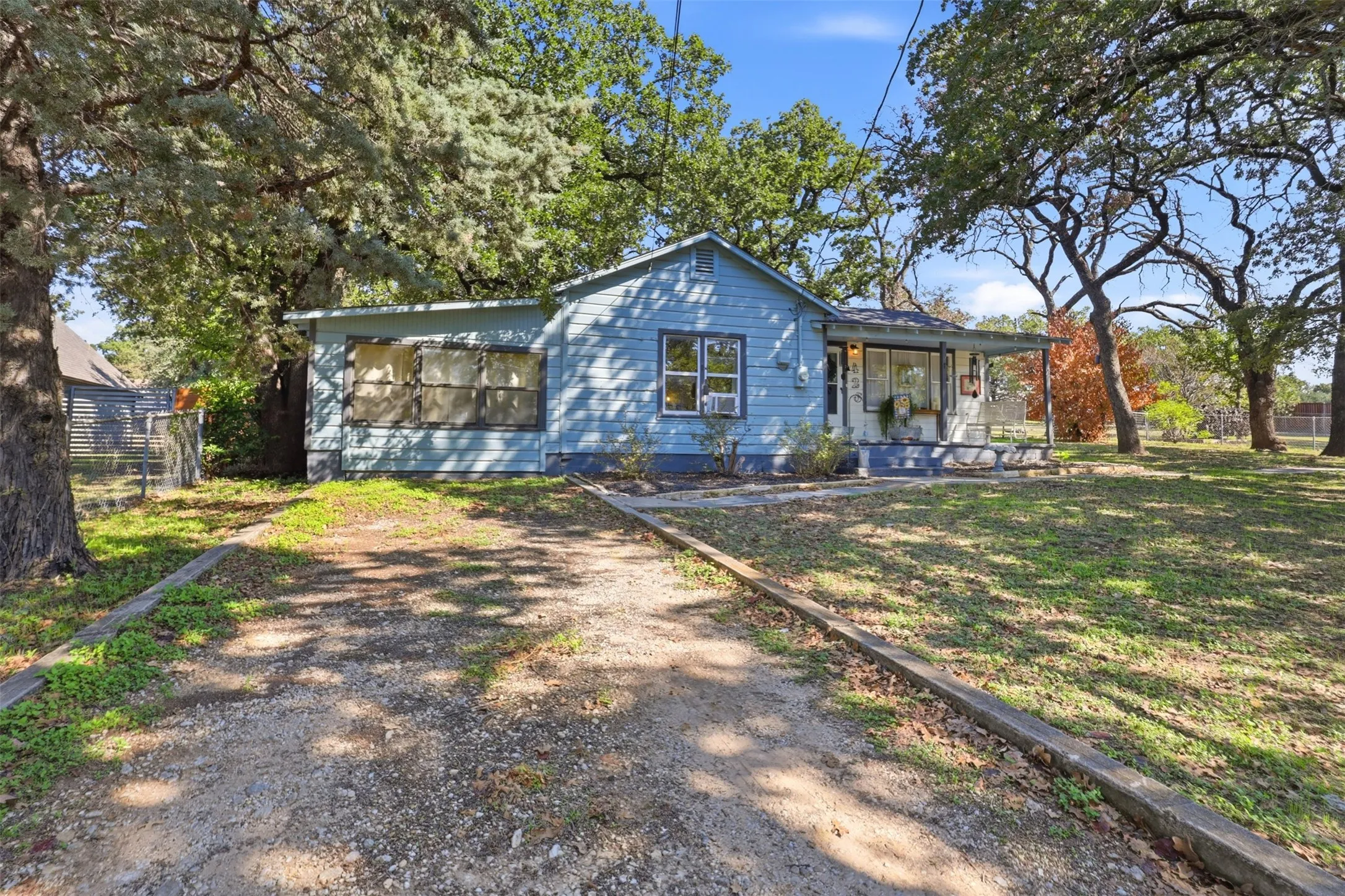 Single-story residence with light blue siding, a covered front porch, and a gravel driveway