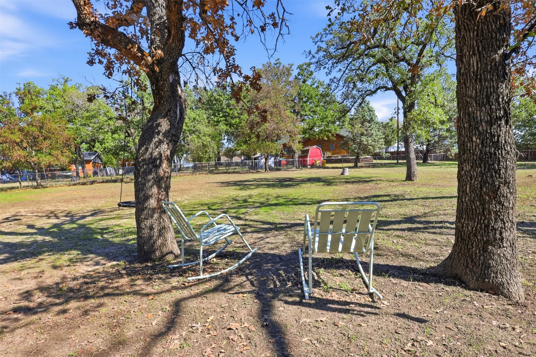 Expansive grassy area with mature trees and a swing