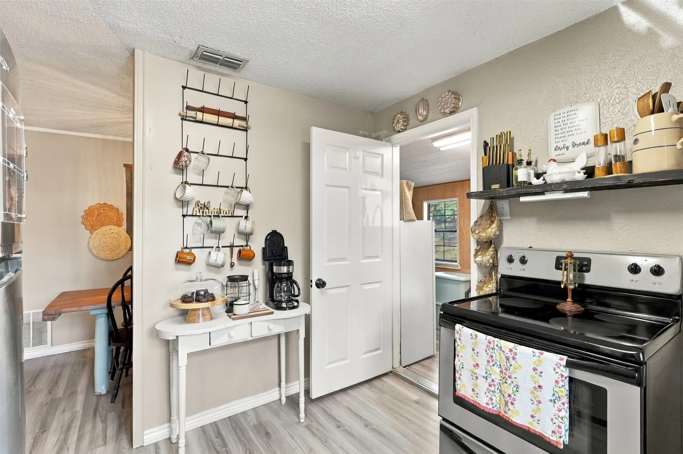 Stainless steel electric range, open shelving, and wood-finish flooring