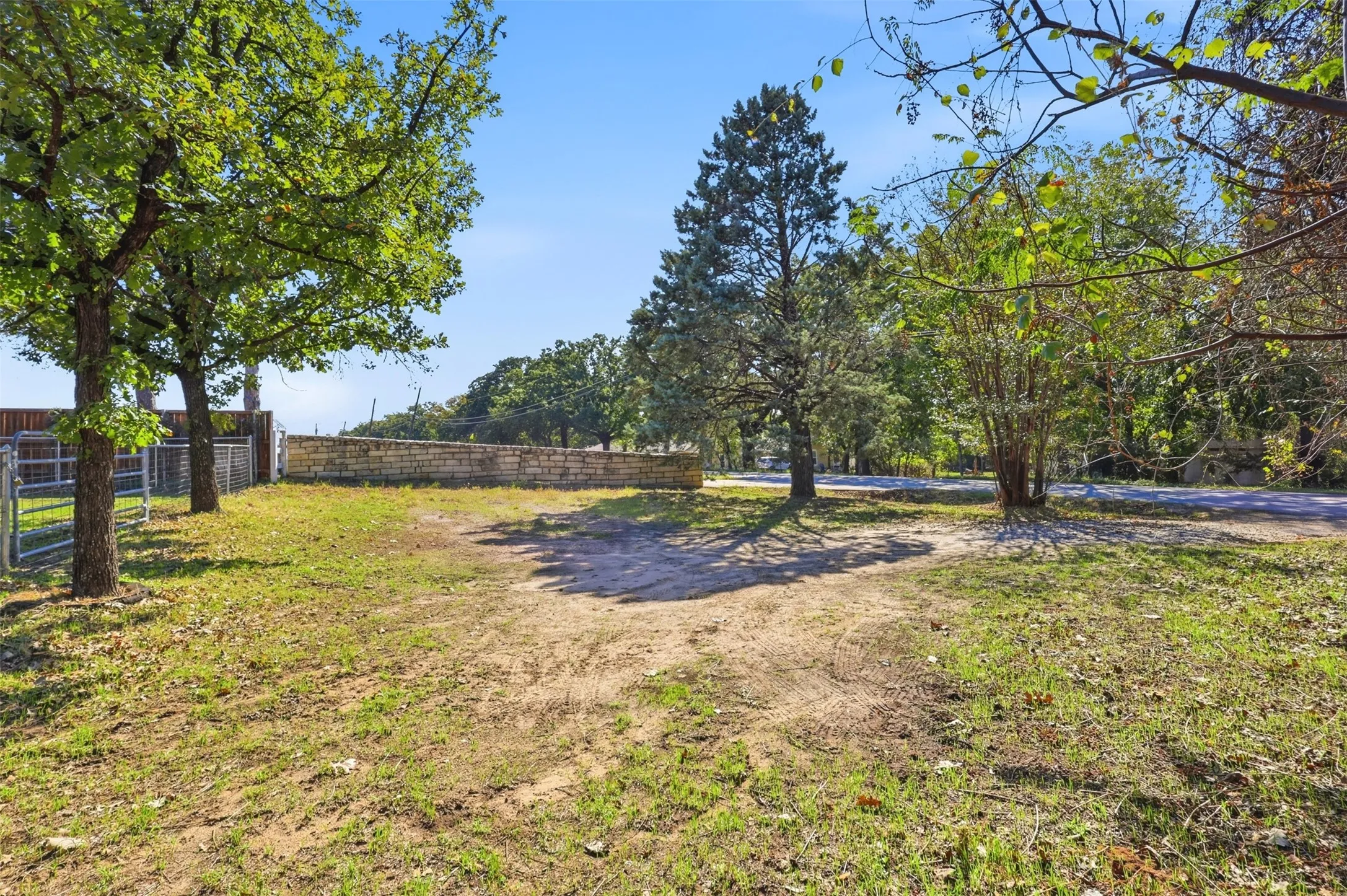 Expansive property featuring mature trees and a stone wall