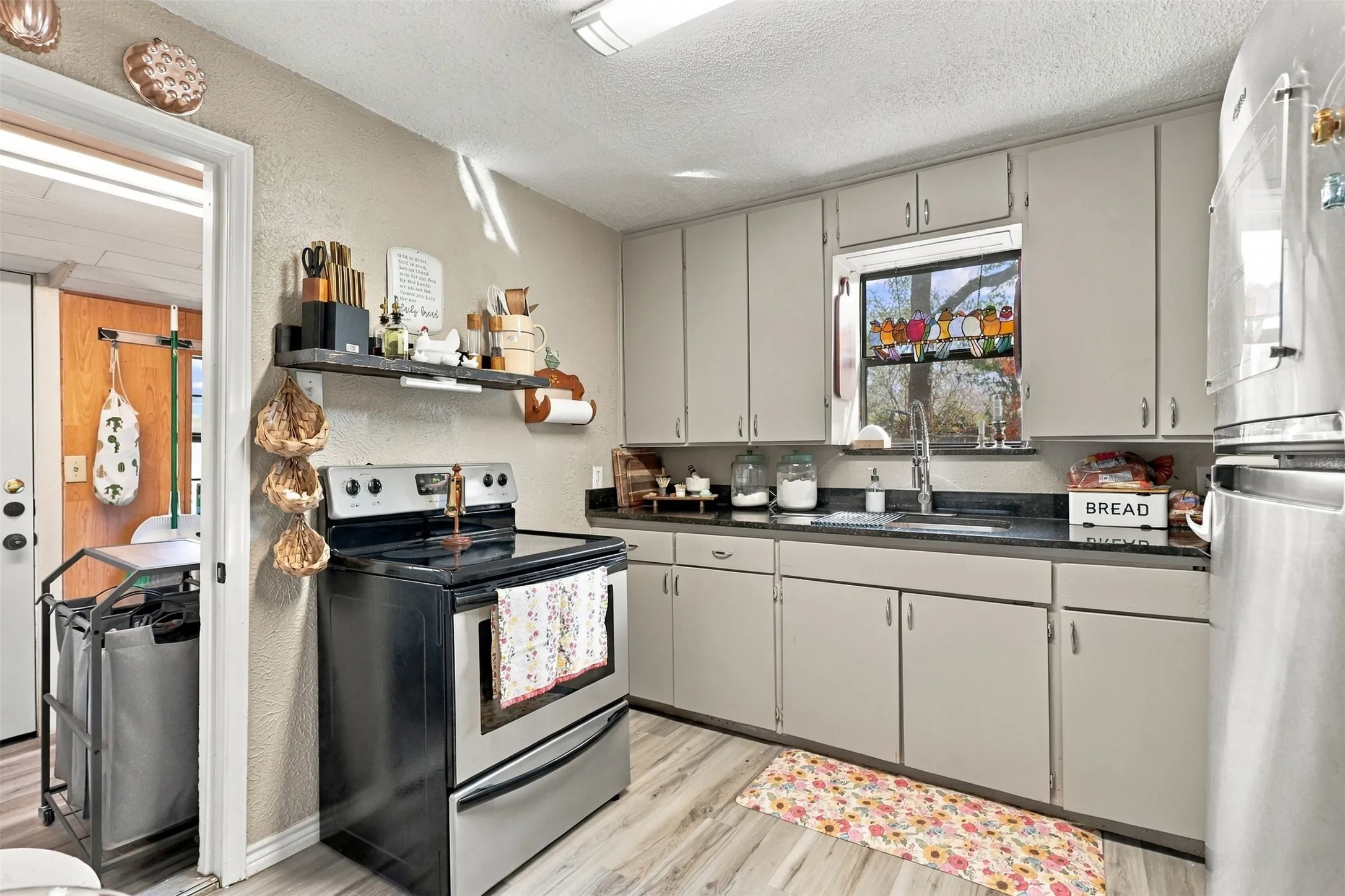 Efficient kitchen featuring soft-gray cabinetry, black stainless steel appliances, and dark countertops