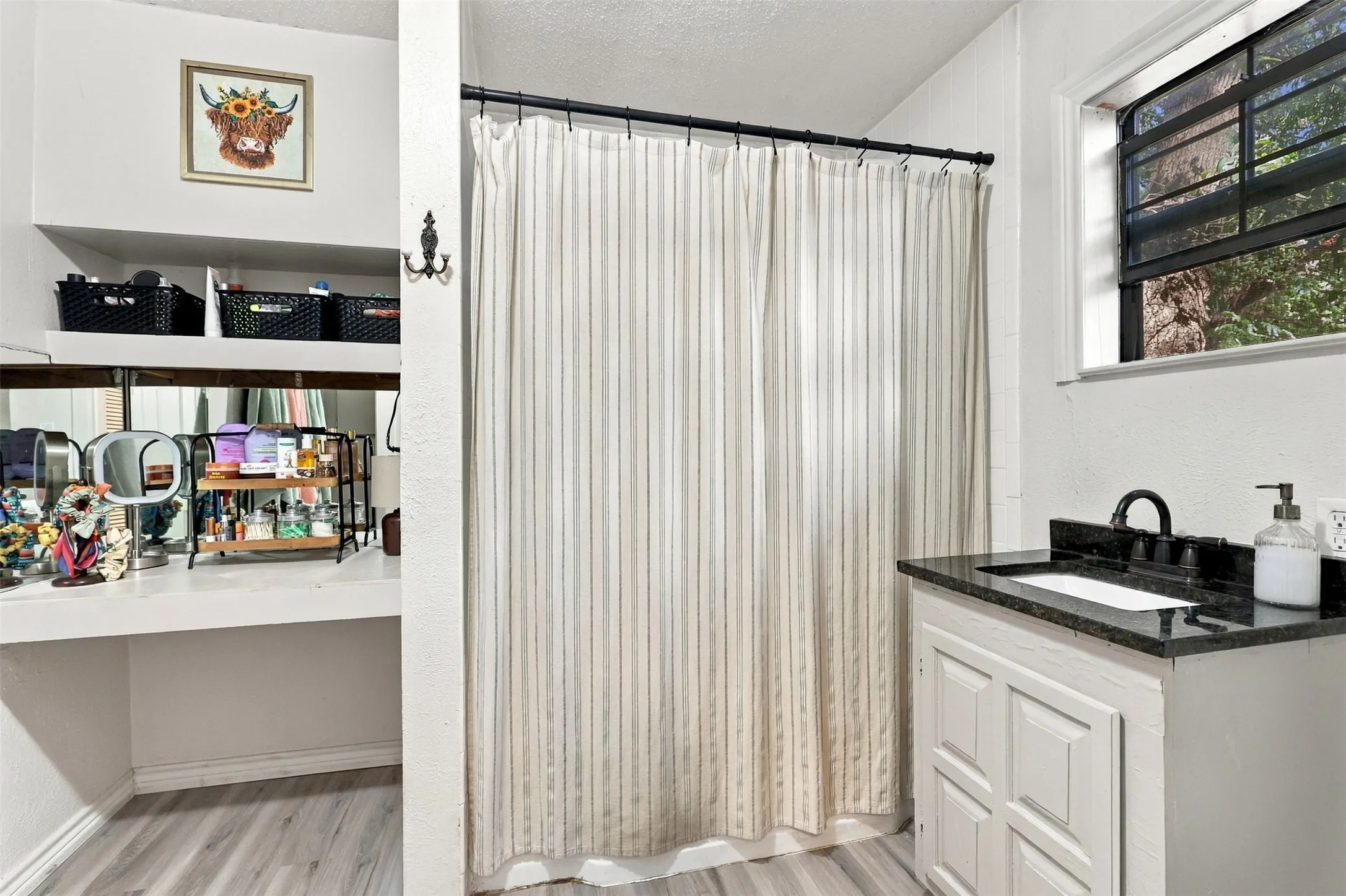 White vanity with a dark countertop and black faucet