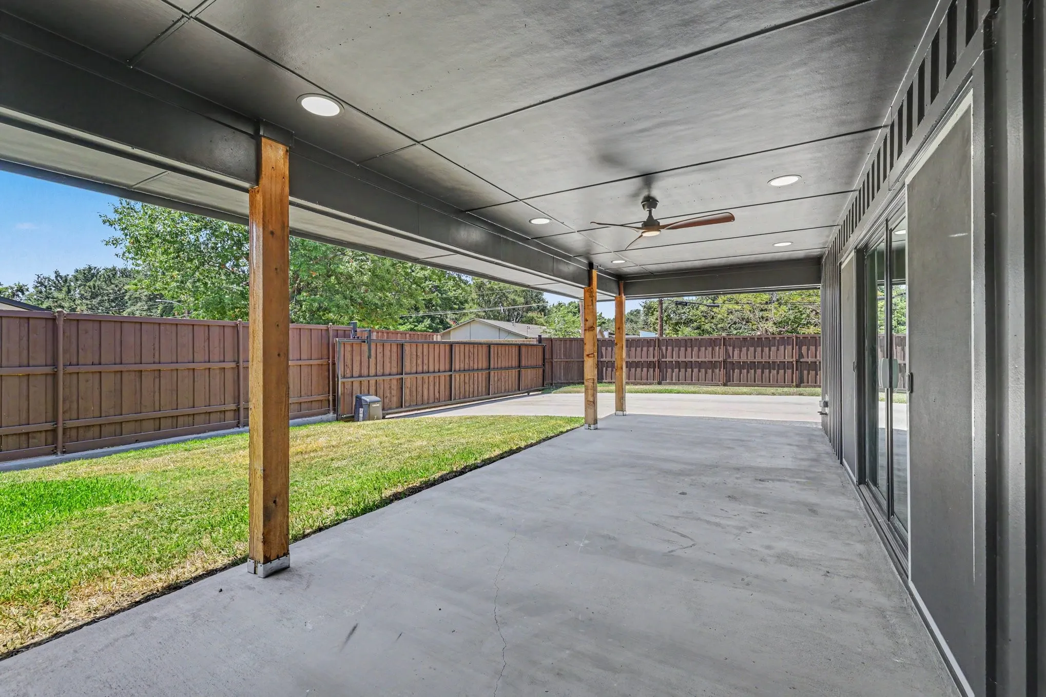 Expansive covered patio featuring a ceiling fan, recessed lighting, concrete flooring, and wood posts