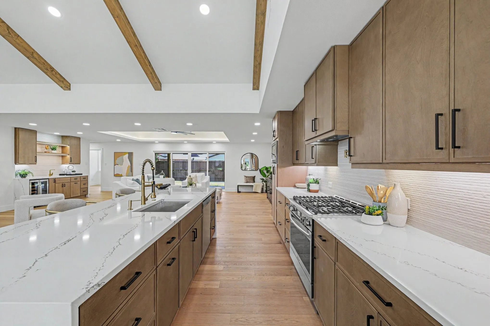 Kitchen featuring a gas range, white quartz countertops, wood-finish flooring, and exposed ceiling beams