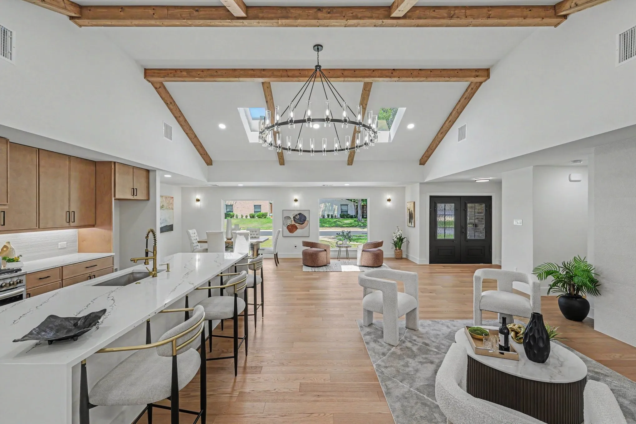 Vaulted ceiling with exposed wood beams, large central skylight, modern chandelier, and wood-finish flooring