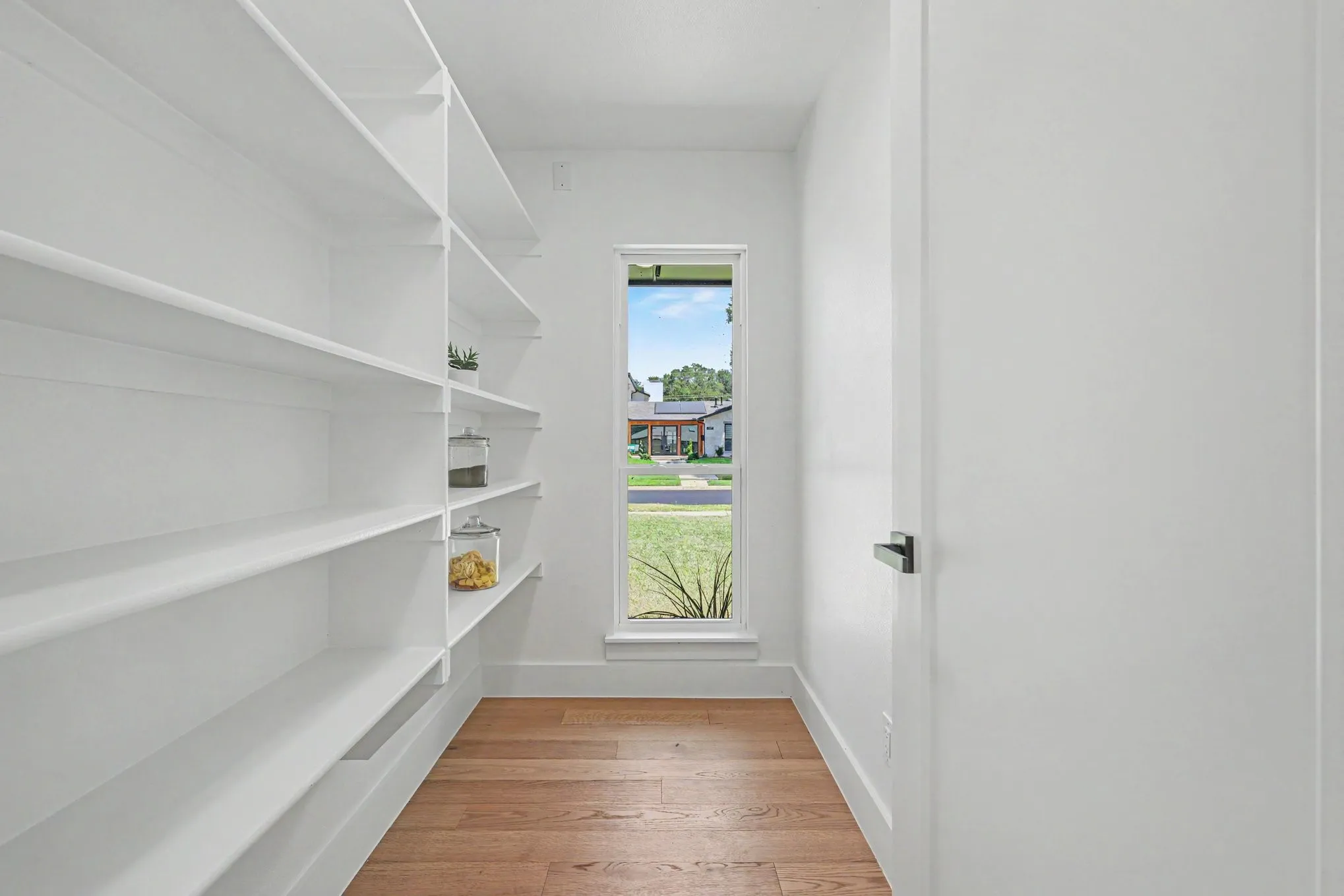 Built-in shelving for ample storage, wood-finish flooring, and a vertical window