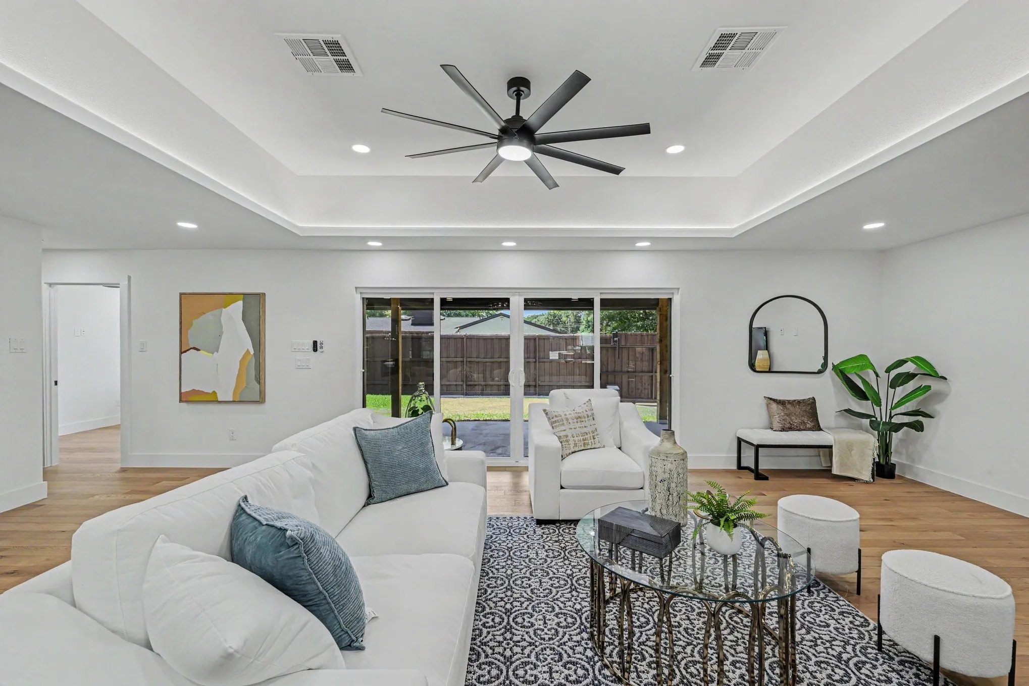 Tray ceiling with recessed lighting and a ceiling fan, wood-finish flooring, and large sliding glass doors