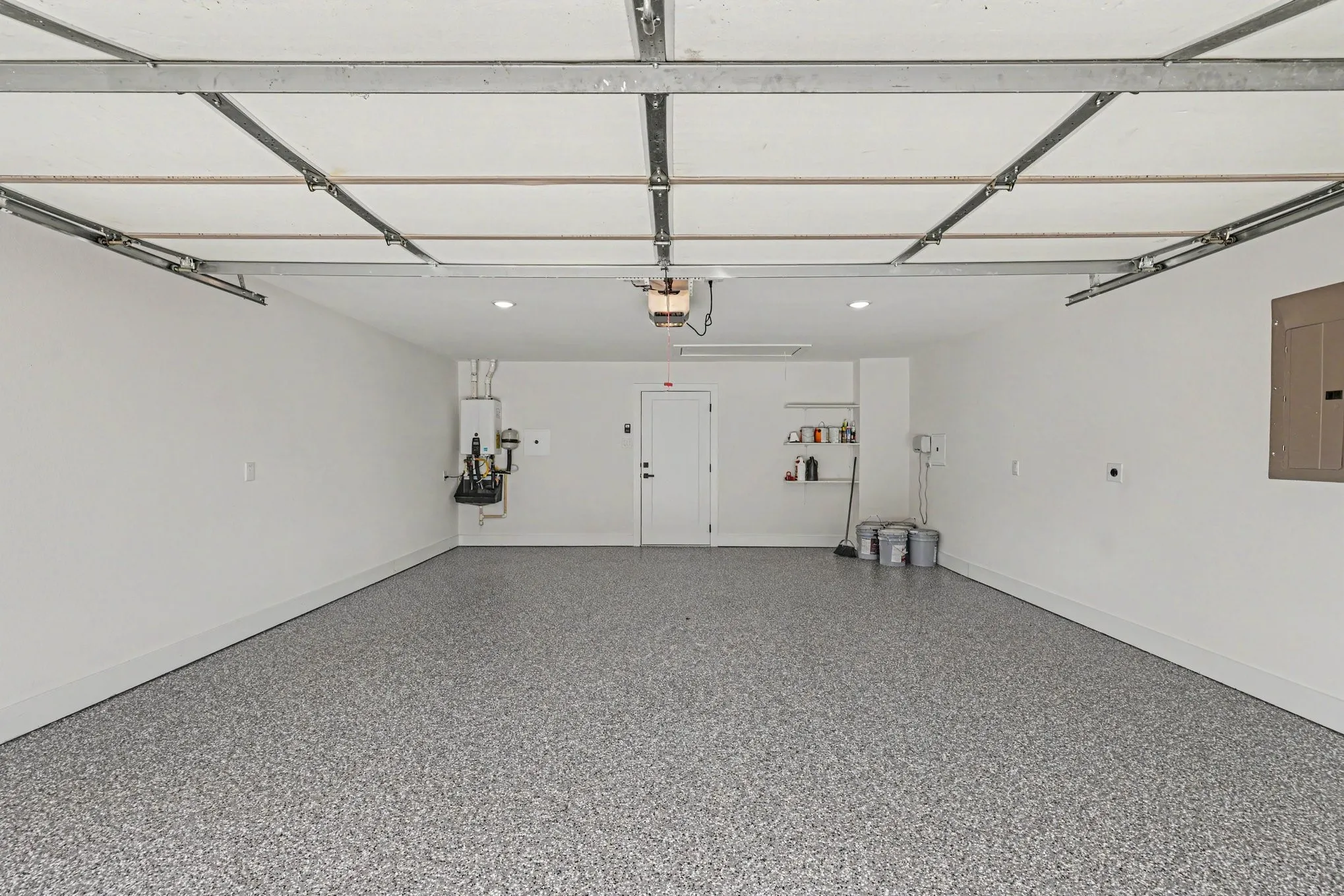Spacious garage with an epoxy floor finish, recessed ceiling lighting, and a tankless water heater