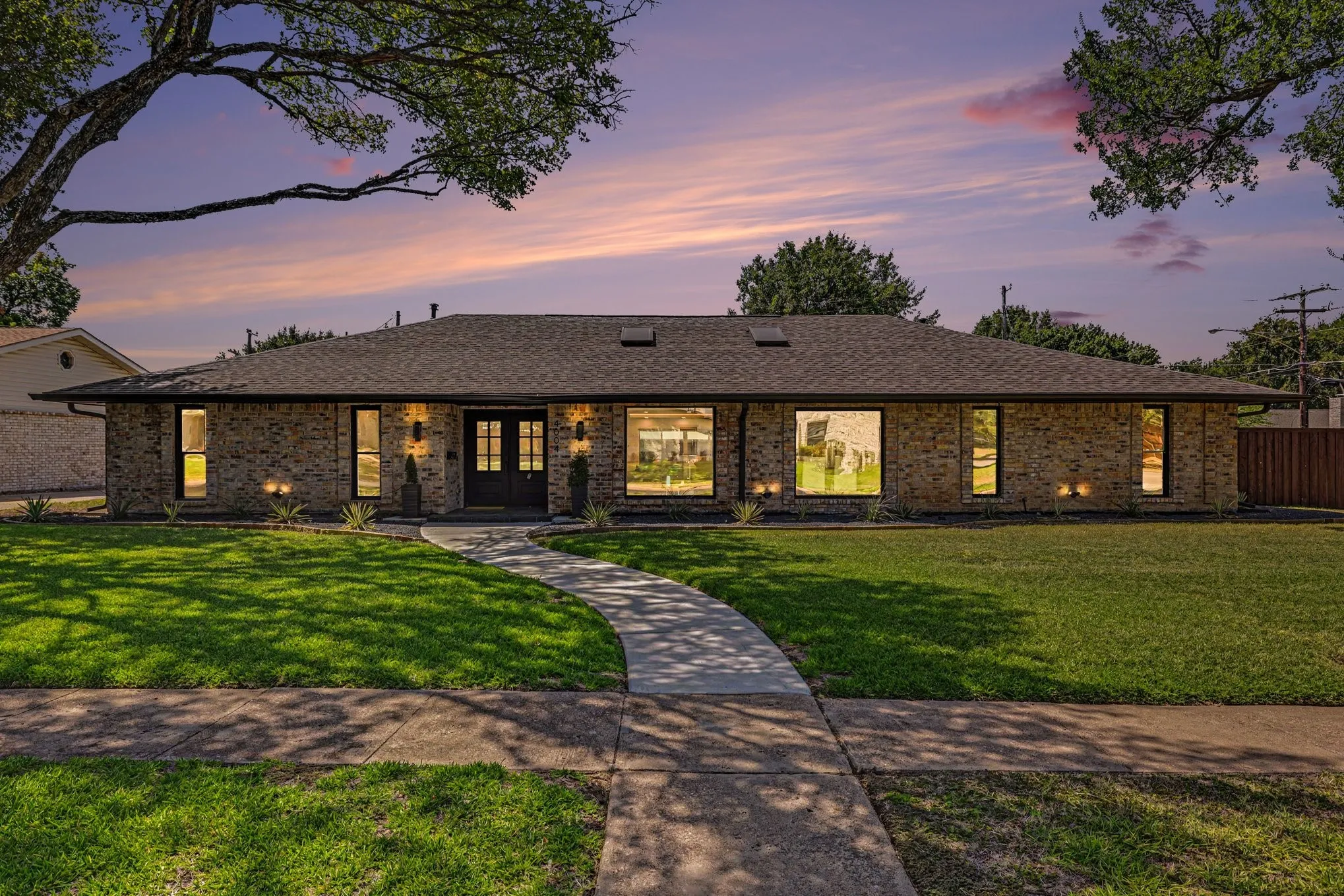 Brick exterior, dual entry doors, multiple large windows, and a concrete walkway