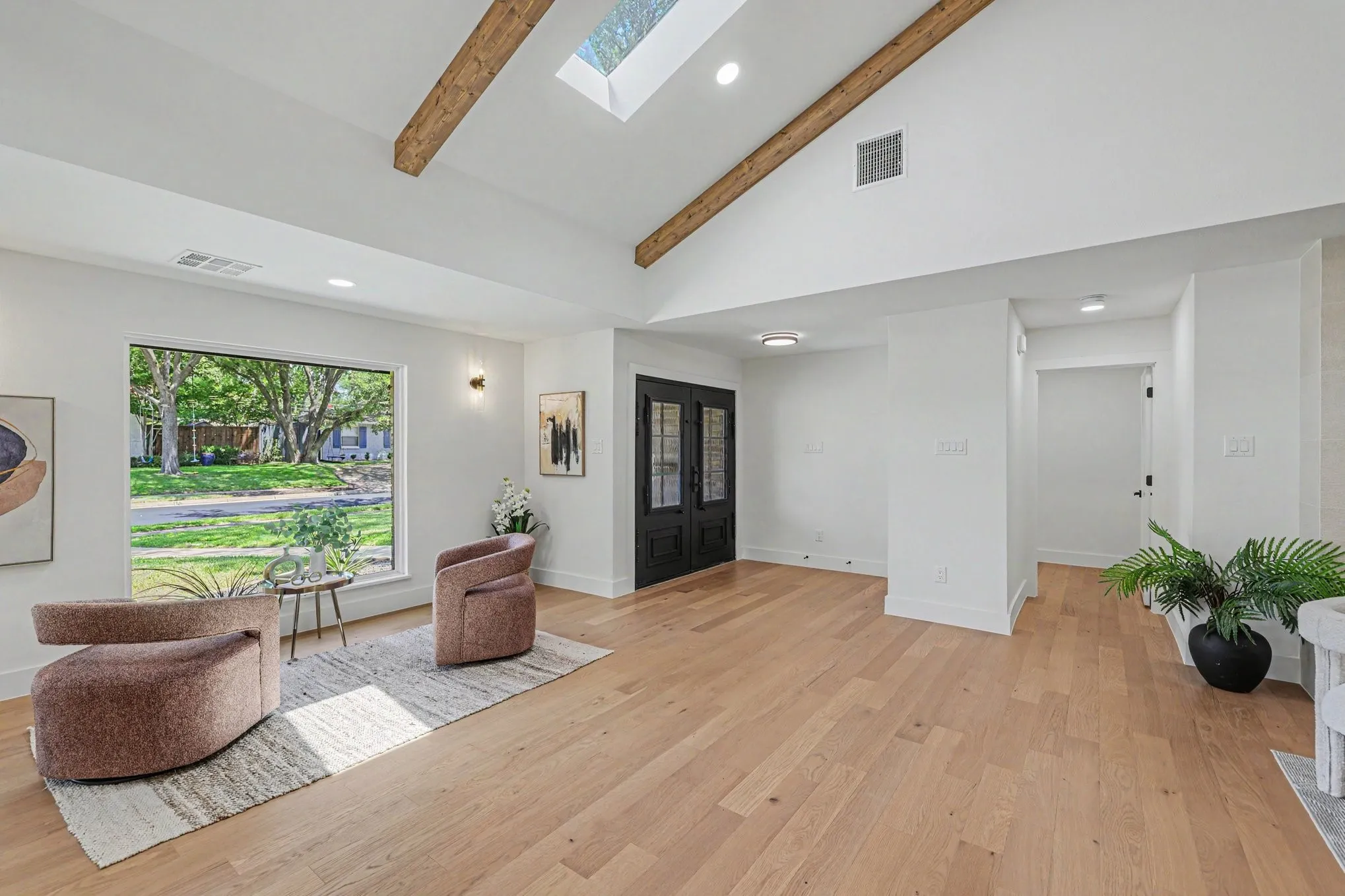 Vaulted ceiling with exposed wood beams, skylight, and recessed lighting