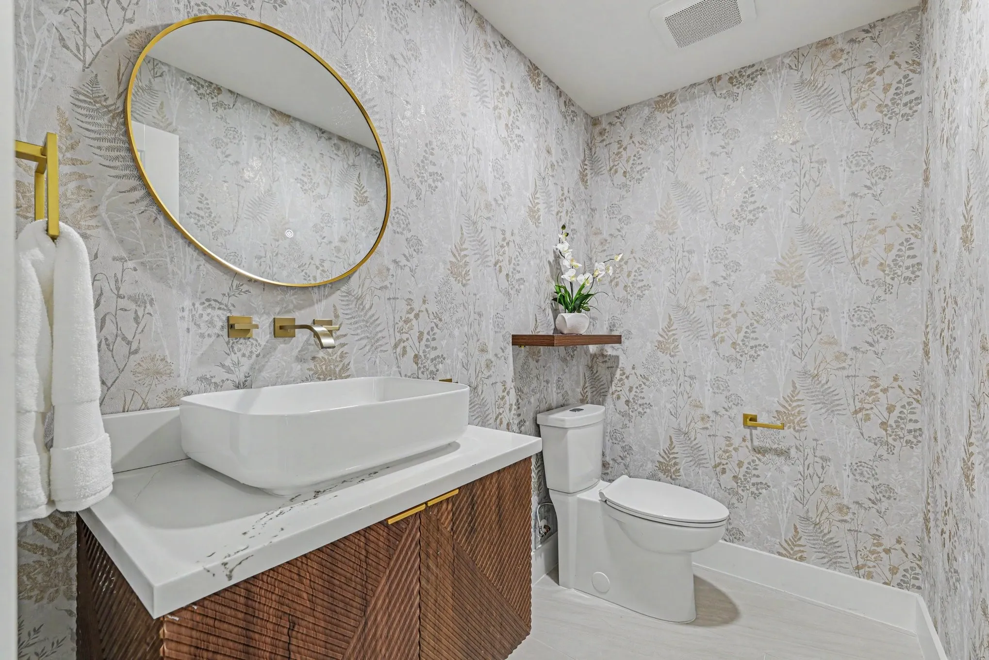 Powder room with a vessel sink, wall-mounted faucet, and patterned wall covering