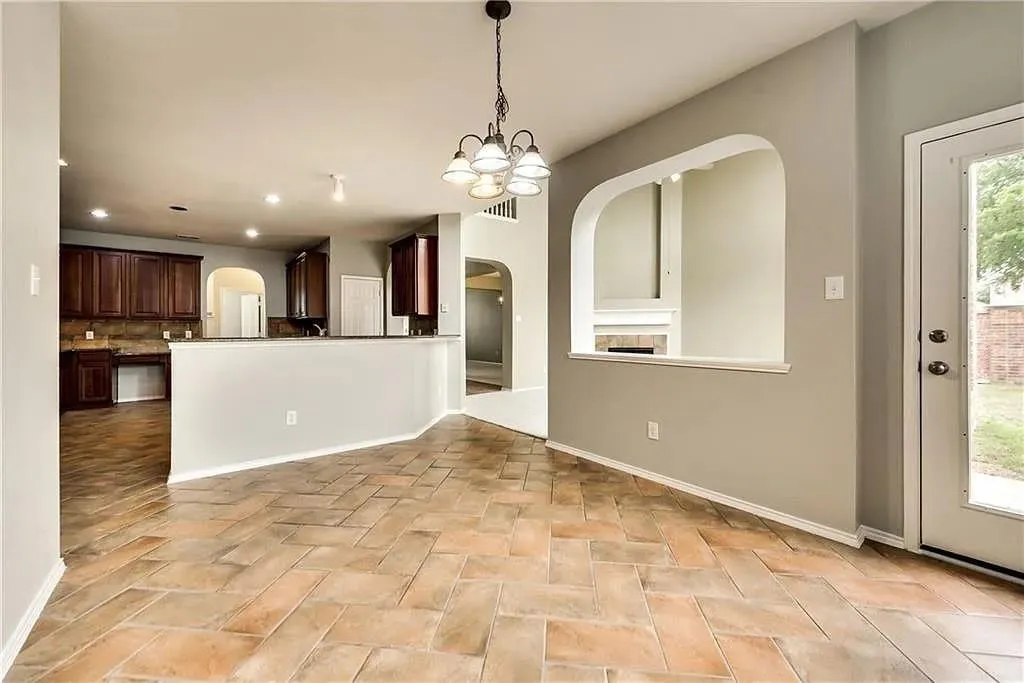 Herringbone pattern tile flooring, arched wall cut-out, built-in cabinetry, breakfast bar, and pendant lighting