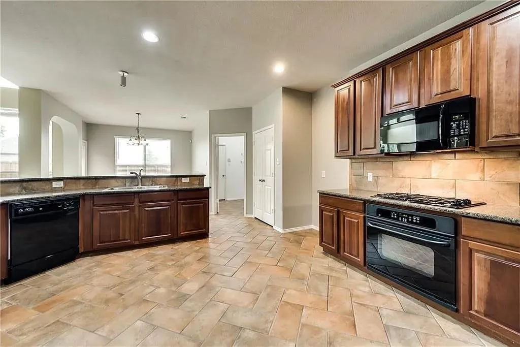 Kitchen featuring wood cabinetry, black appliances, a tile backsplash, and tile flooring
