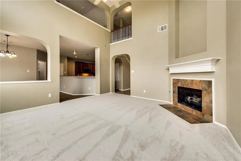 Two-story ceilings, arched doorways, tiled fireplace, and a second-story balcony