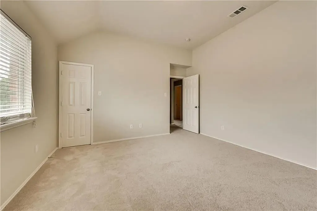 Vaulted ceiling, neutral wall paint, light-colored carpet flooring, window with blinds, panel doors