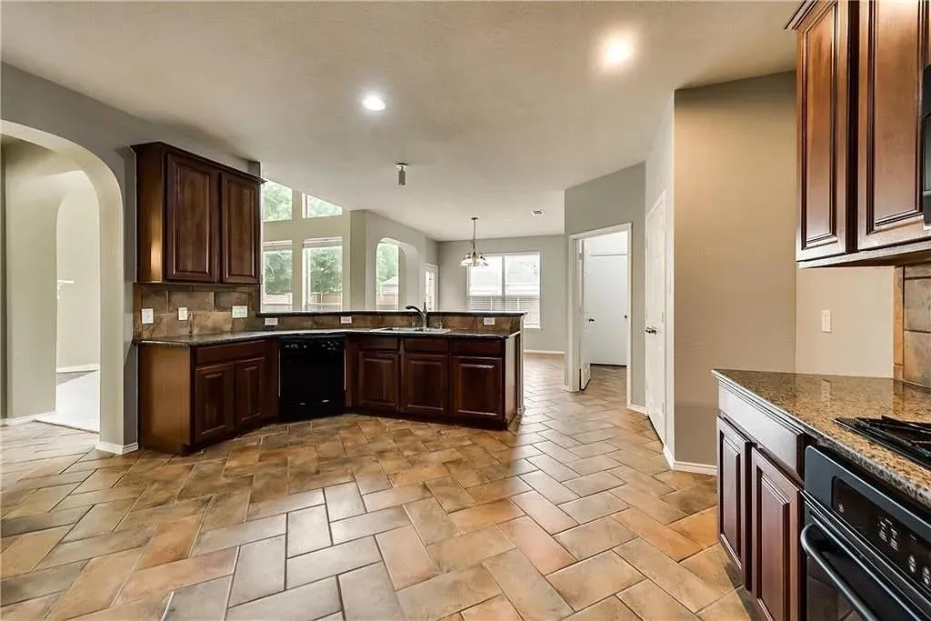 Kitchen featuring herringbone pattern tile flooring, dark wood cabinetry, a built-in oven, and a double basin sink