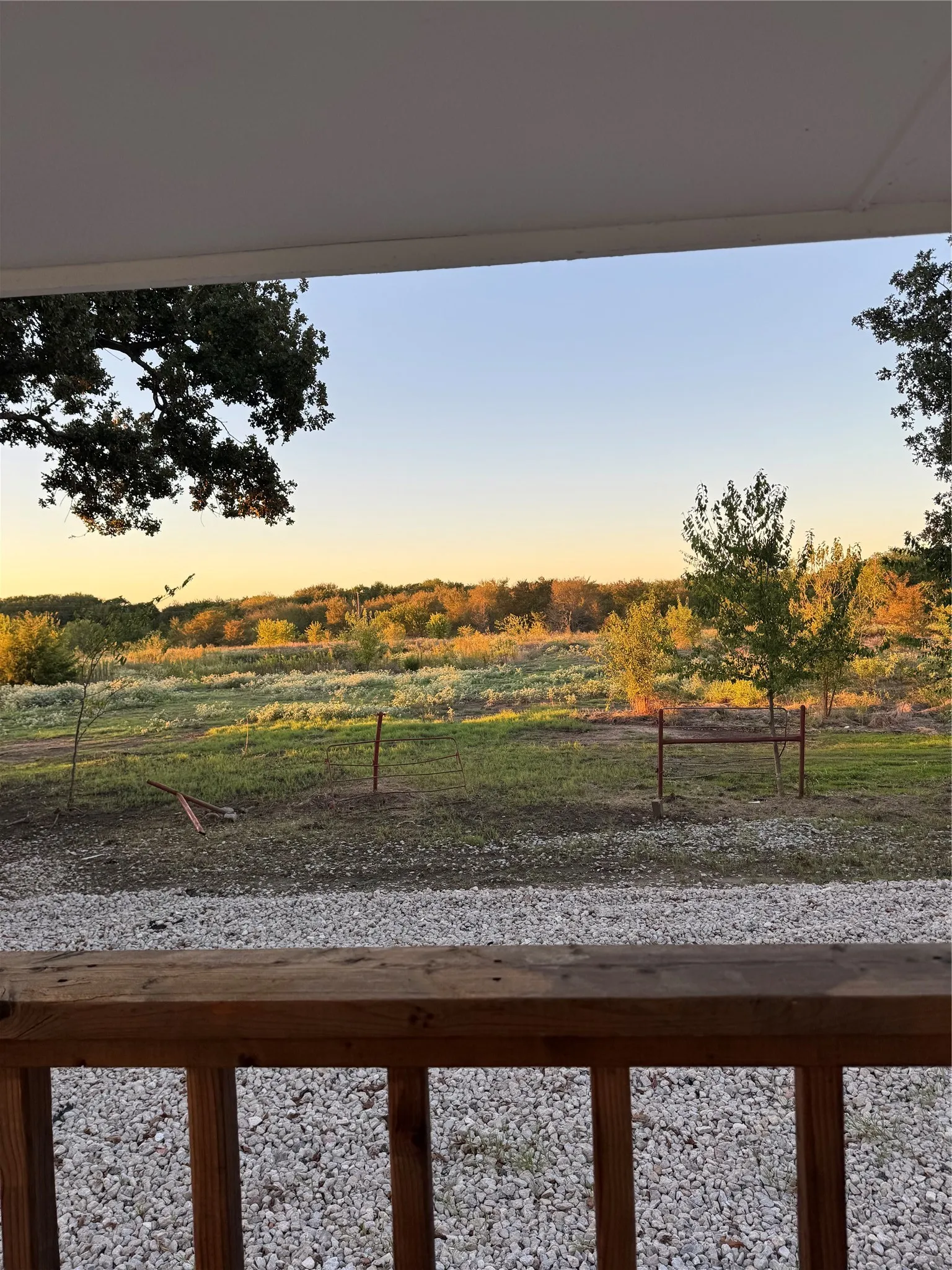 Wooden railing with visible grain, gravel ground covering, and distant natural landscape
