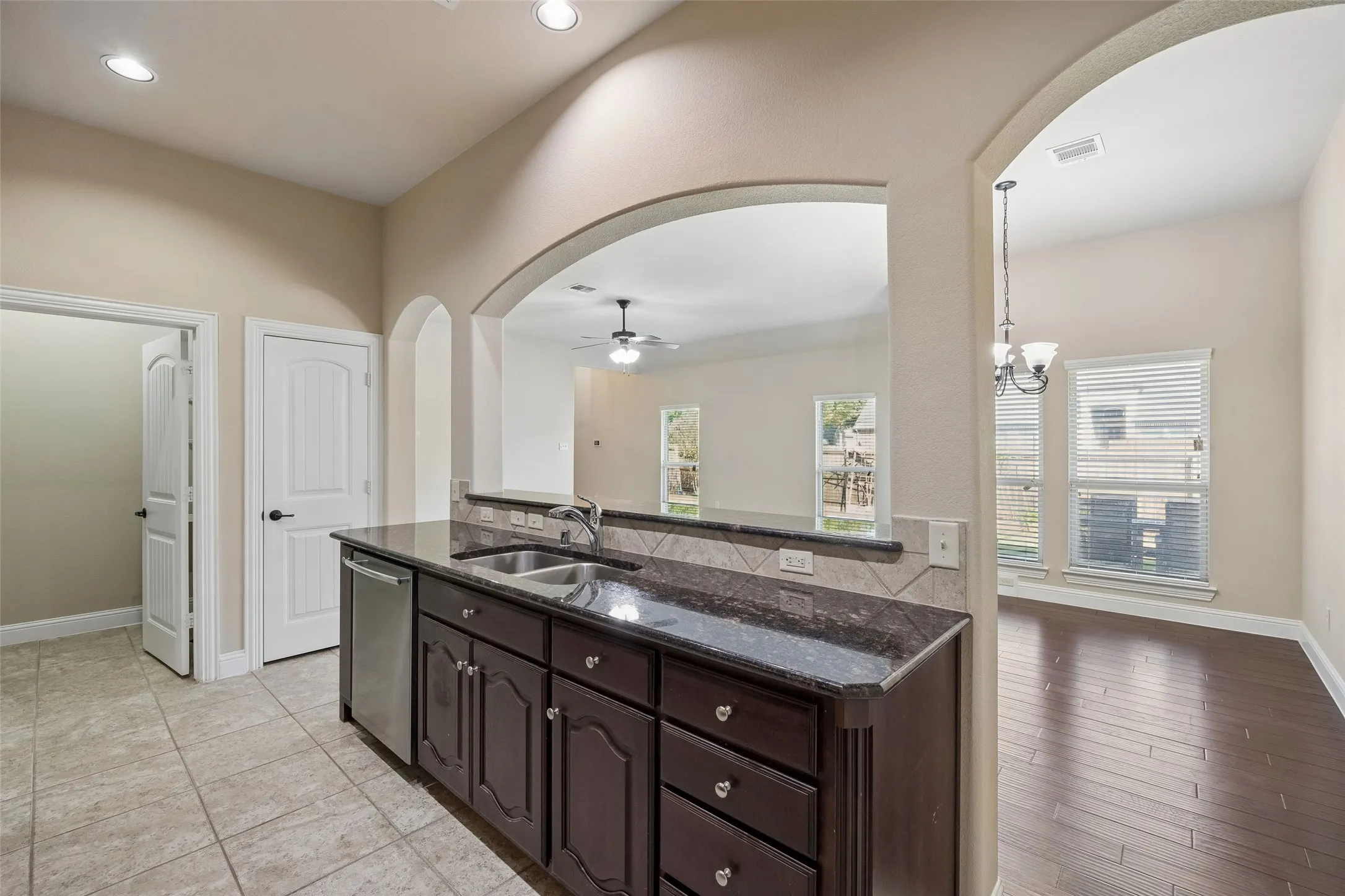 Granite countertops, dark wood-finish cabinetry, and stainless dishwasher