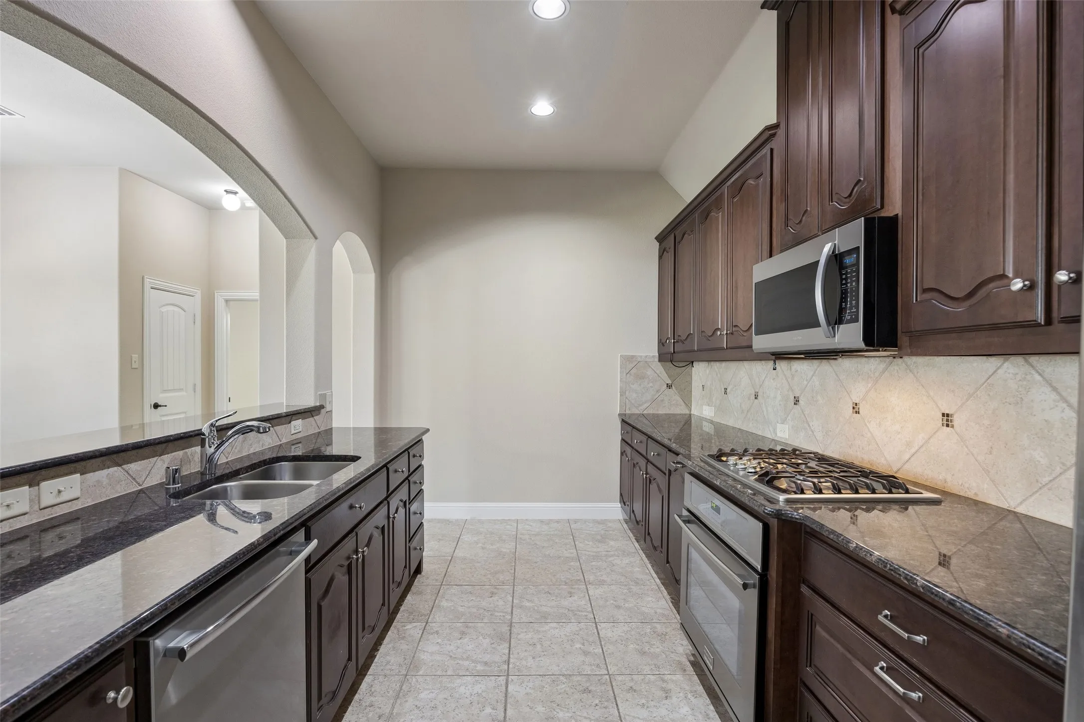 Dark wood cabinetry, stainless steel appliances, granite countertops, gas cooktop, pot drawers