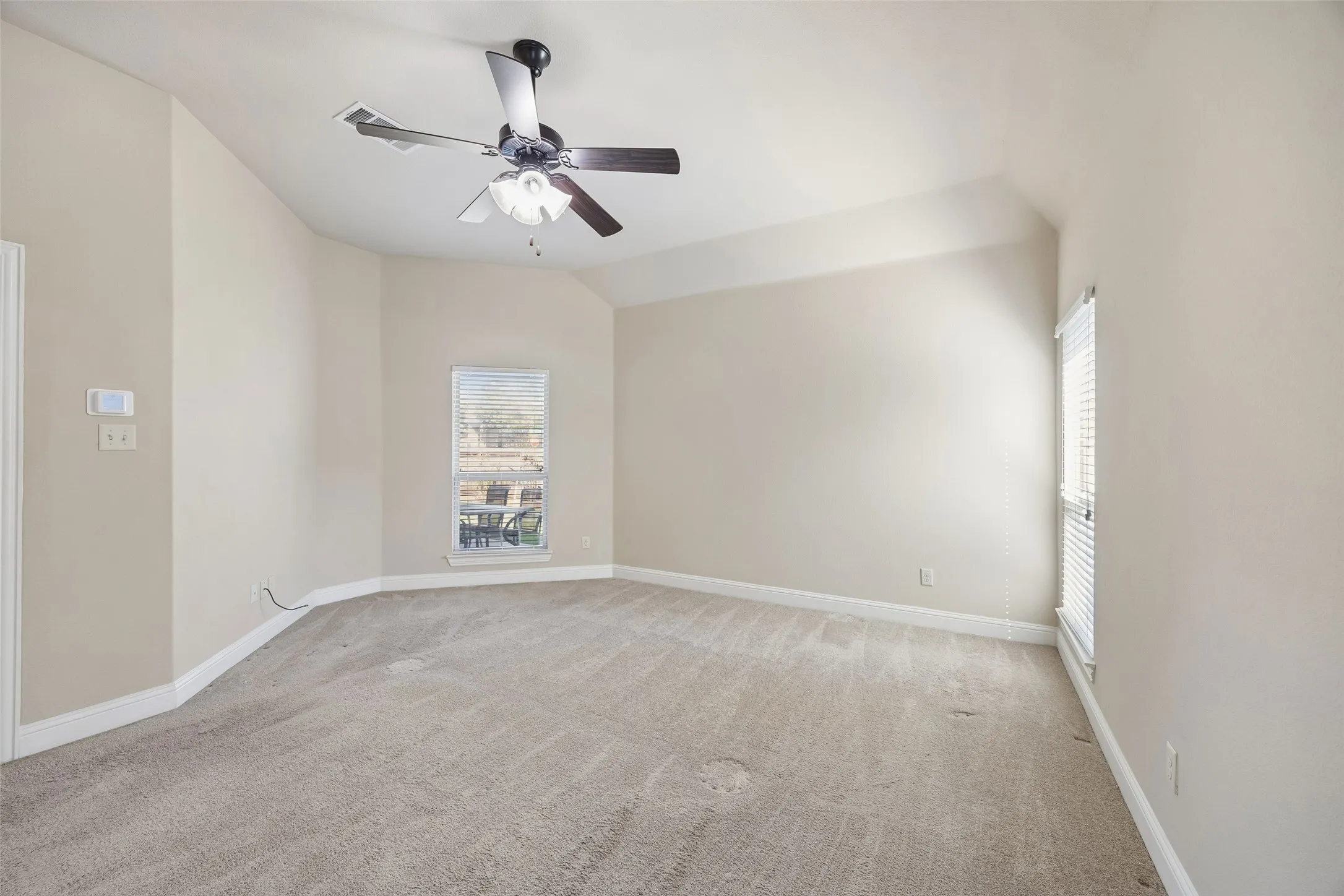 Angled walls with neutral paint, light-toned carpet flooring, and a ceiling fan with integrated lighting