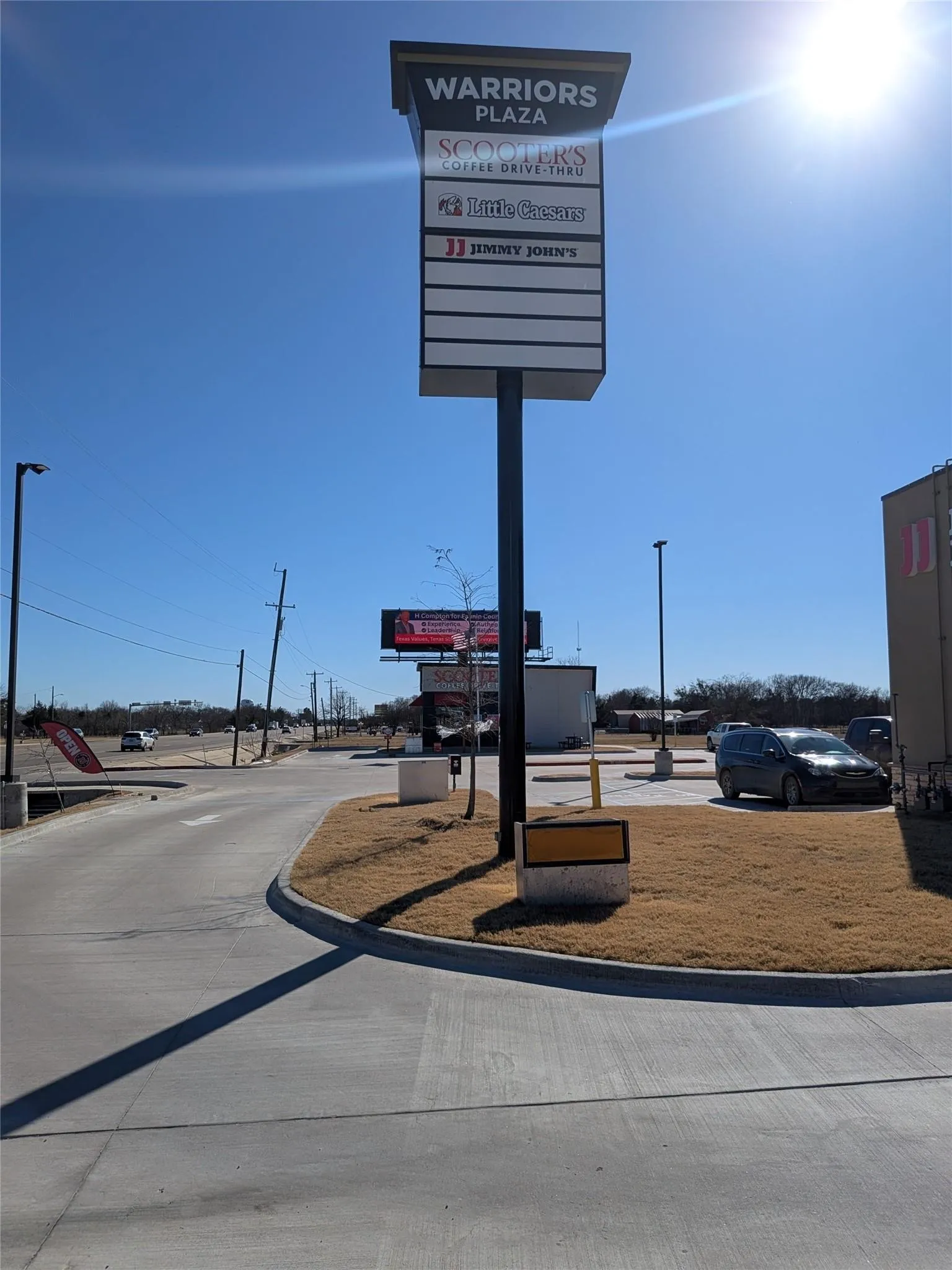 Retail center pylon sign with tenant listings, concrete drive, and landscaped areas